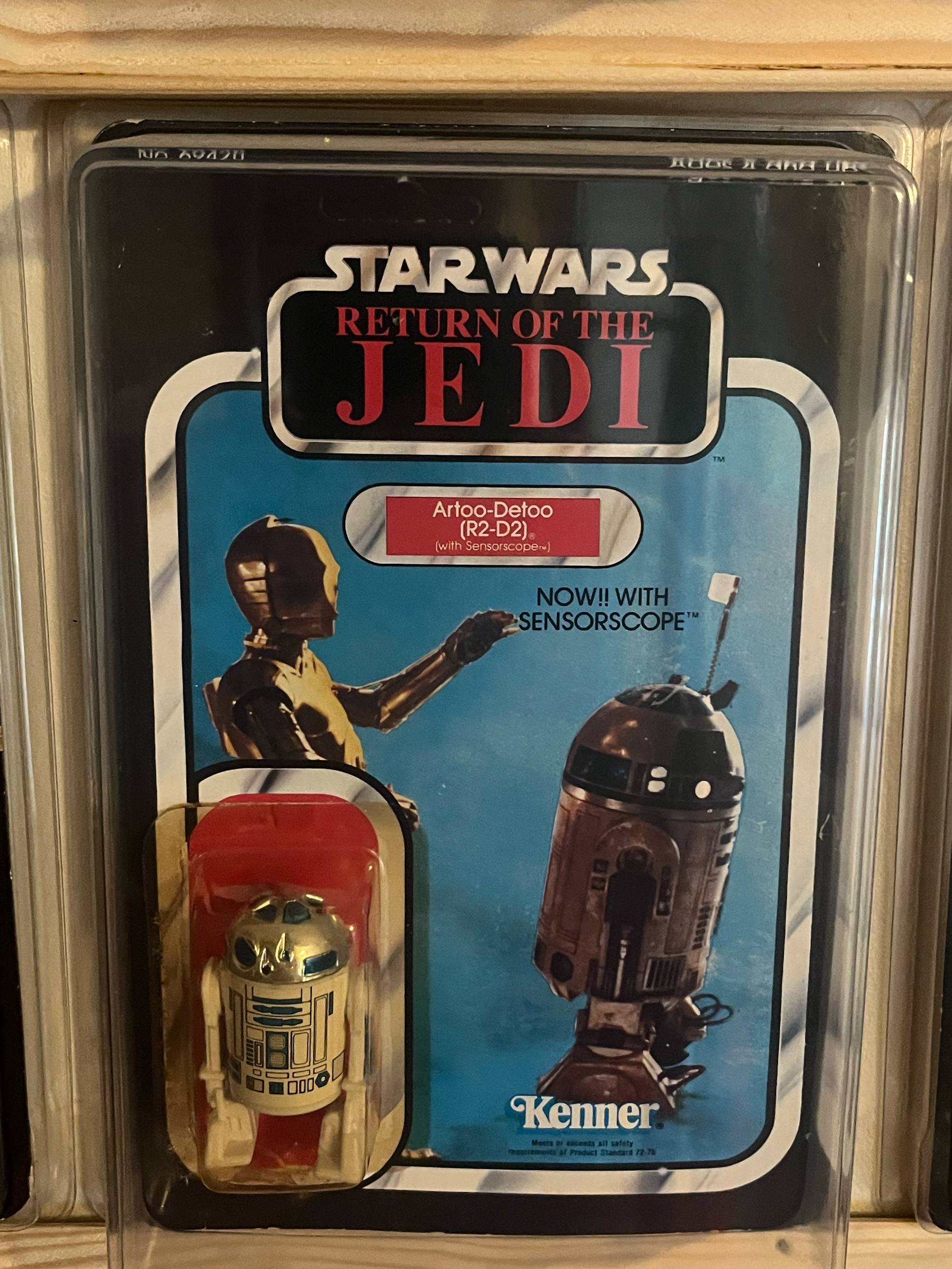 Star Wars Star Wars: The Empire Strikes Back action figure set in clear plastic packaging, featuring a figure and a can with a robot design, on a wooden surface.