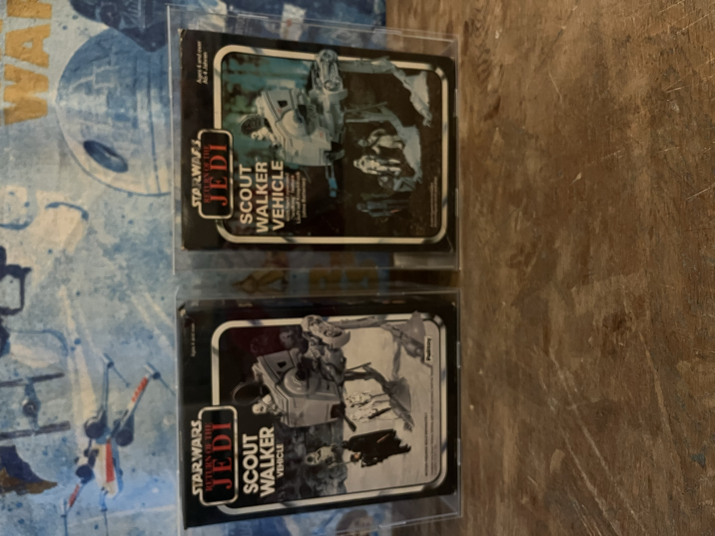 Collection of Star Wars memorabilia, including boxed figures of character Jyn Erso and other Star Wars characters, arranged on a wooden surface with a blue wall in the background.