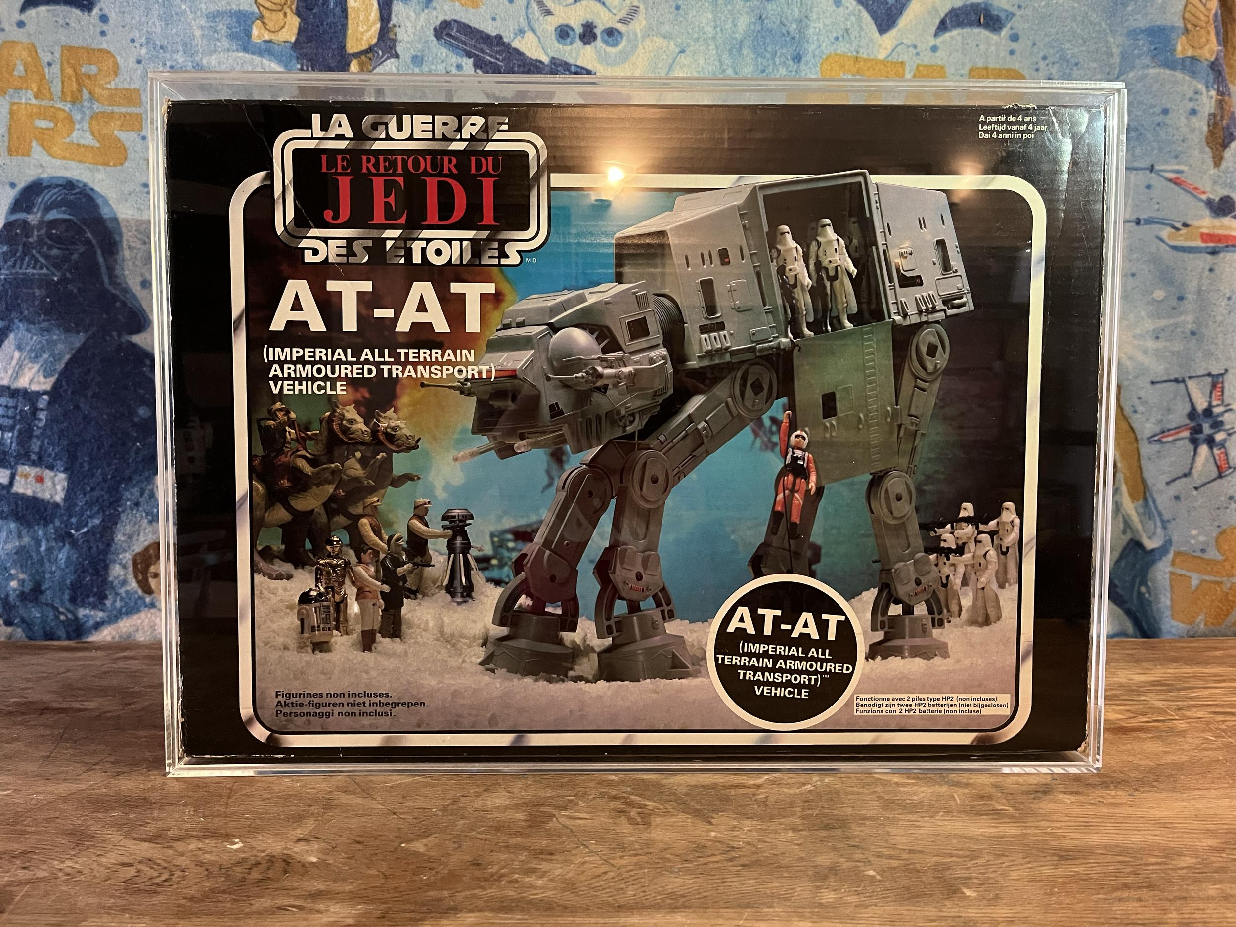 A boxed set of Star Wars action figures and vehicles, featuring an AT-AT Imperial all terrain armored transport vehicle with miniature figures, set against a colorful background.