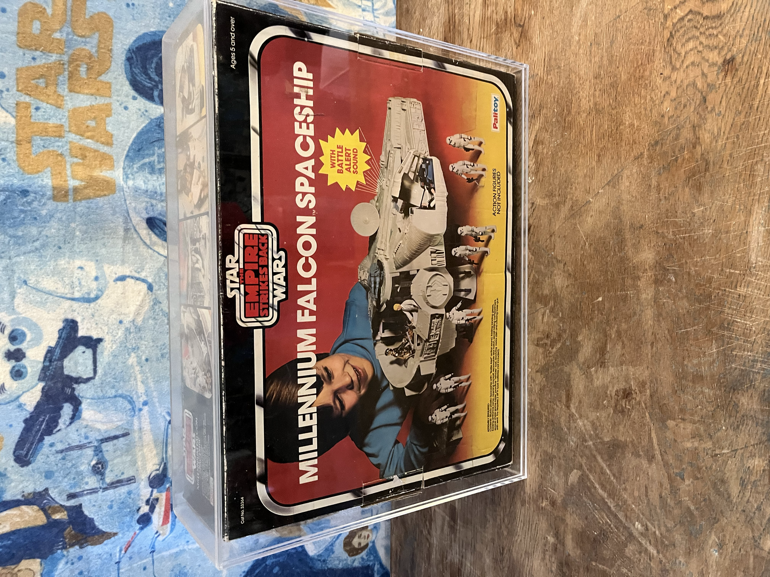 A plastic box with a set of Star Wars-themed Millennium Falcon model and Star Wars figurines inside, with a colorful background featuring text and designs.