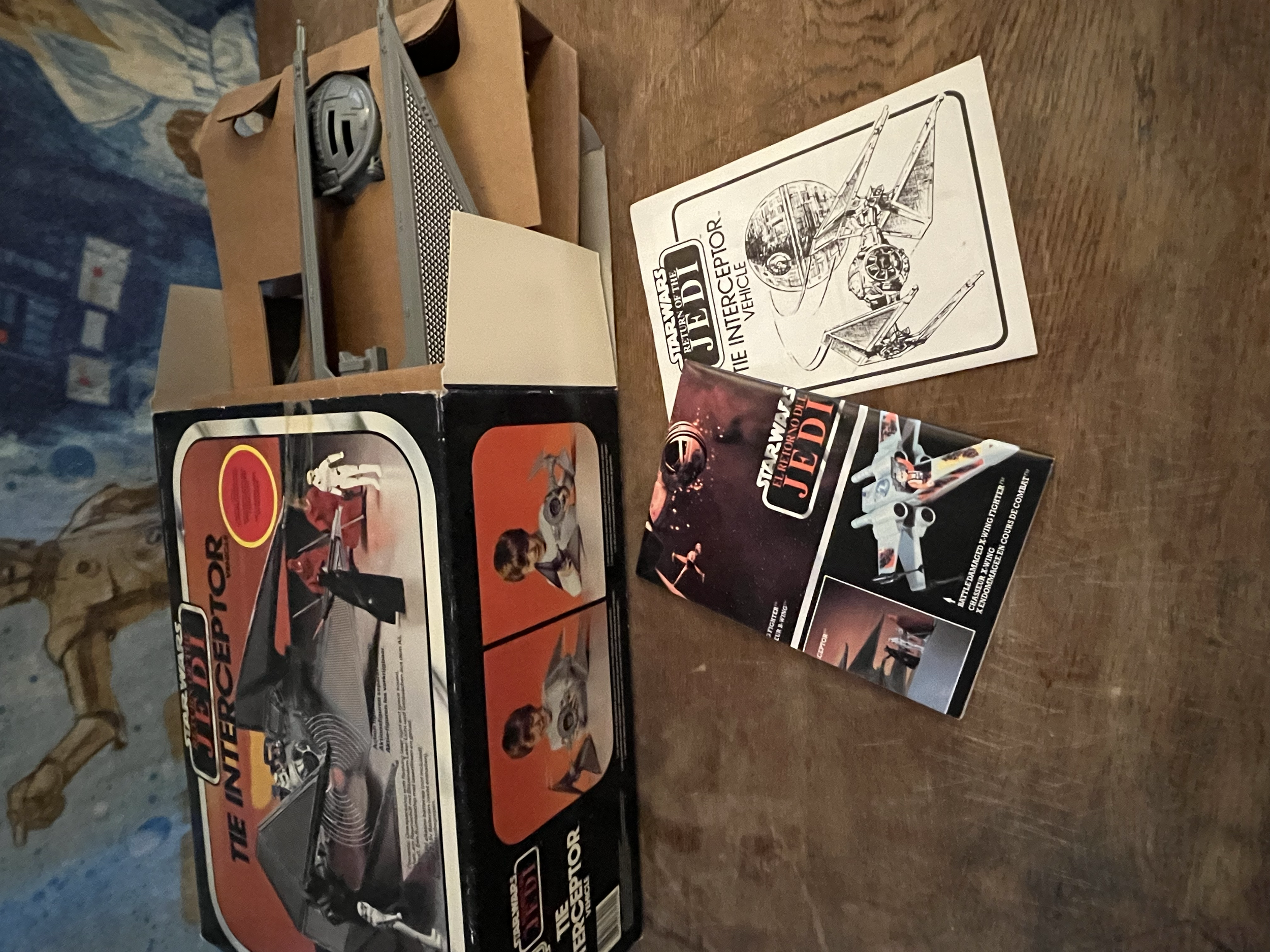 Collection of Star Wars-themed toy boxes and manuals, including a Millennium Falcon instruction booklet placed on a wooden table.