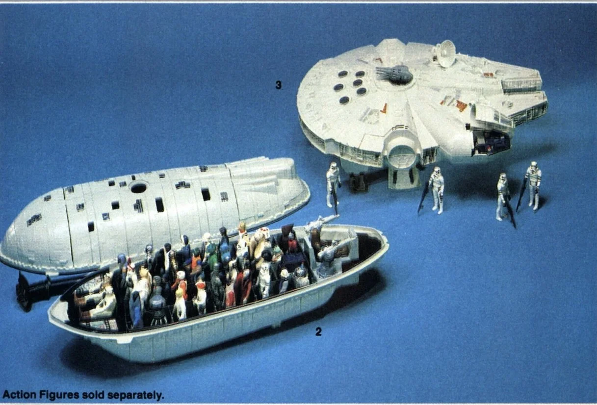 Model of the Millennium Falcon spaceship from Star Wars with action figures and astronauts surrounding it, displayed on a blue surface.
