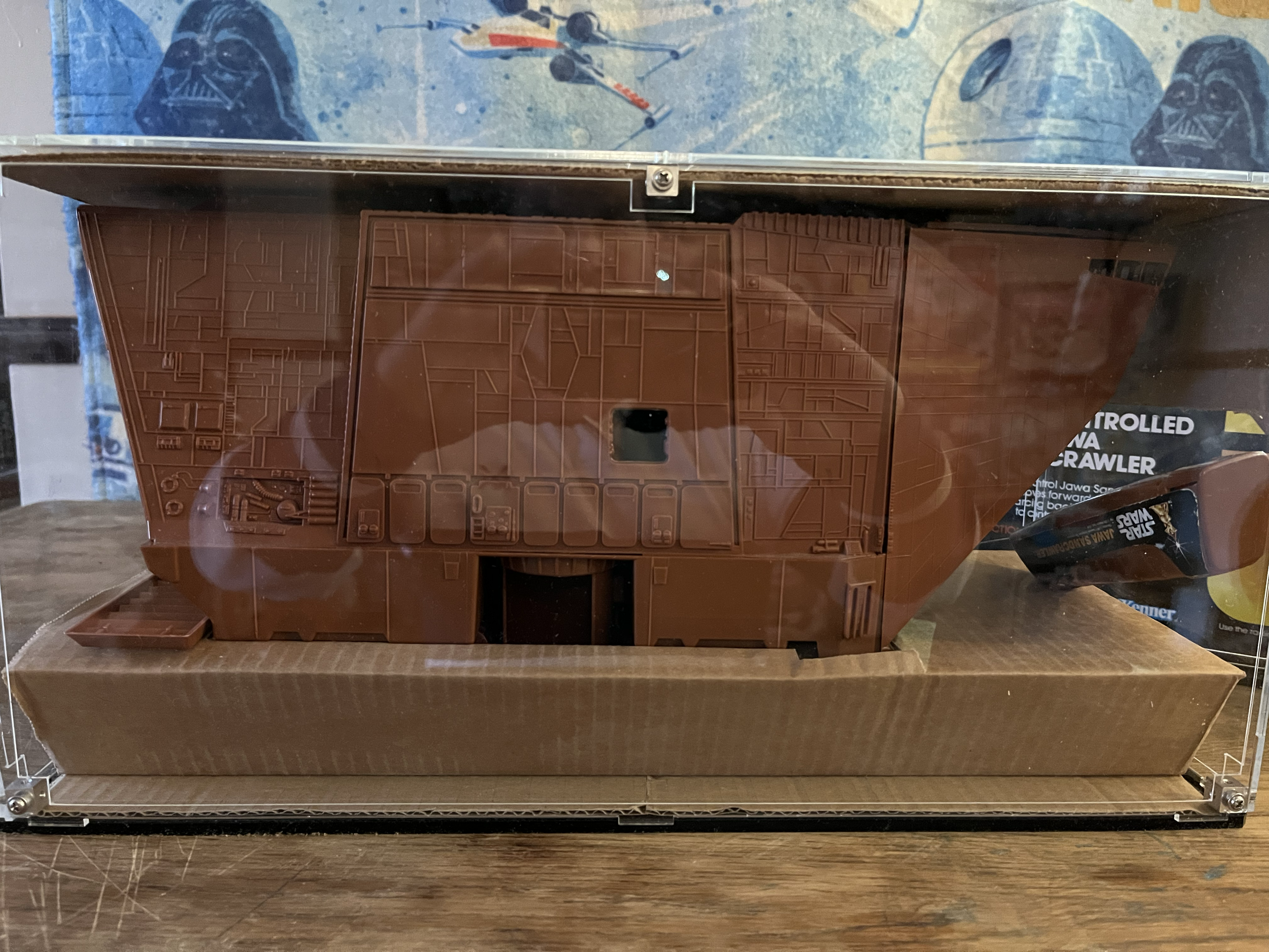 A model of the Millennium Falcon spaceship from Star Wars, displayed inside a glass case on a wooden surface.