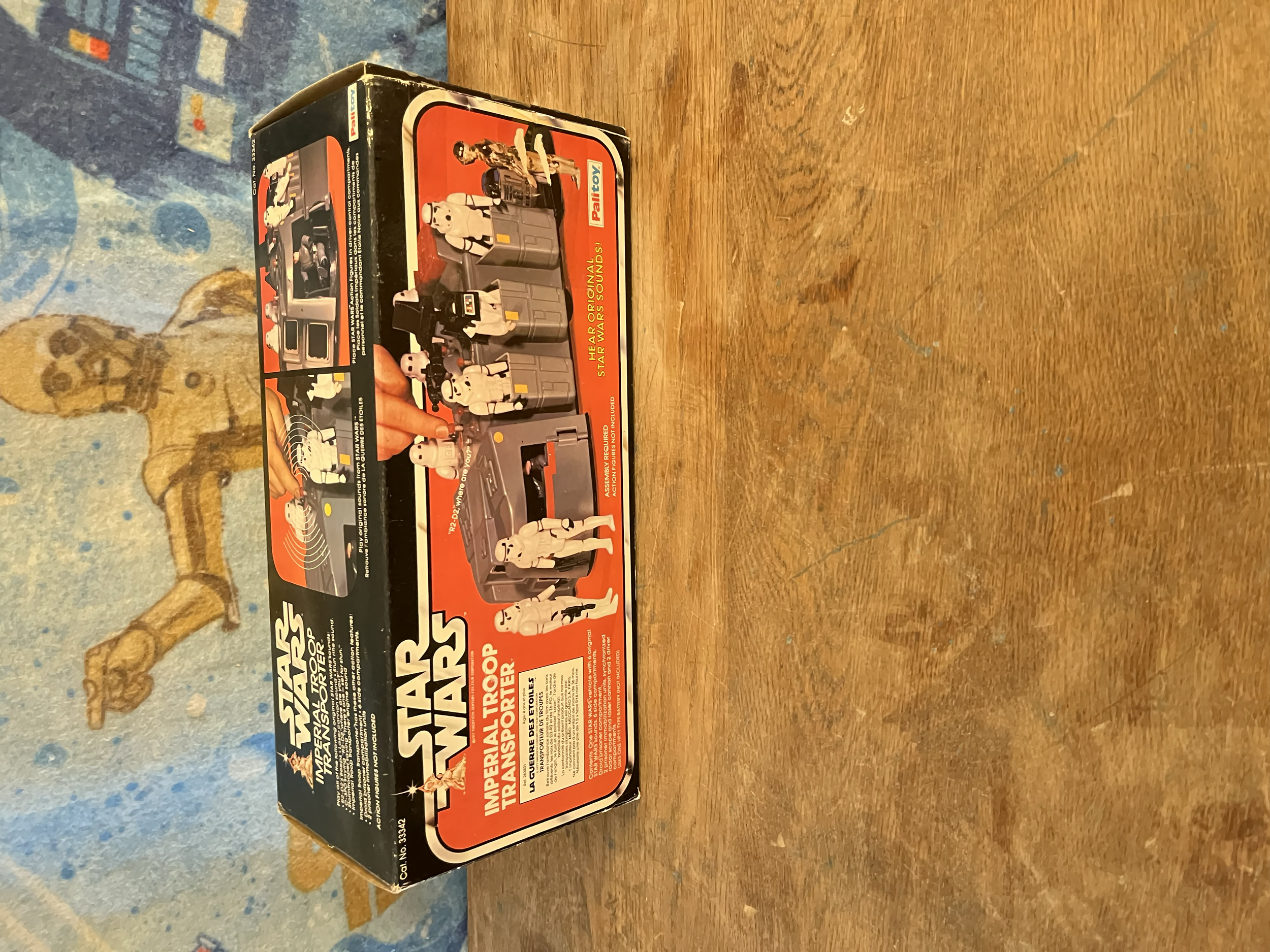 Star Wars Return of the Jedi toy box depicting characters like stormtroopers, princess Leia, and Darth Vader. The box is placed on a wooden surface with a colorful, cartoon-like background.