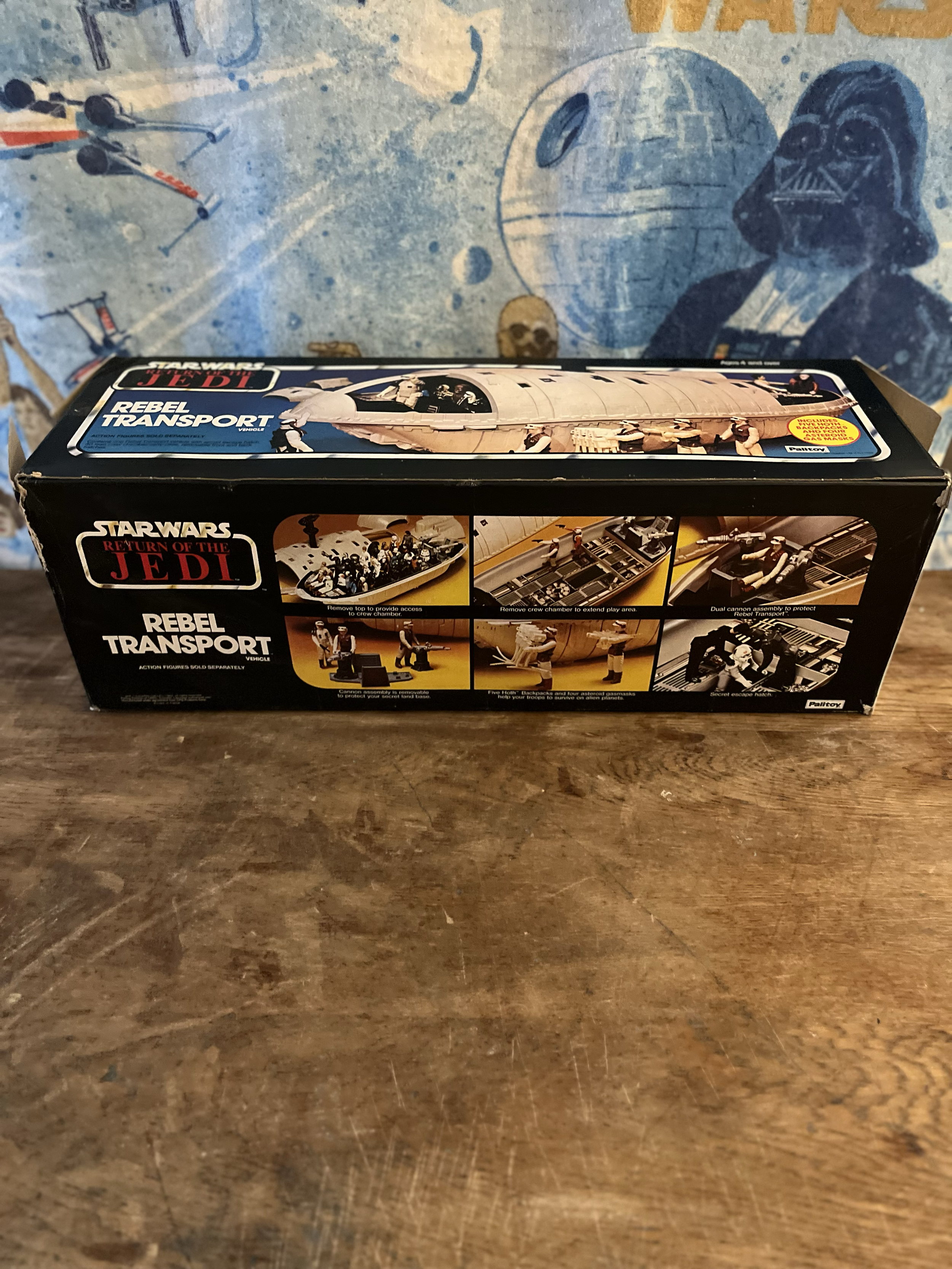 A toy set of the Rebel Transport from Star Wars Return of the Jedi on a wooden surface countertop with a blue and planet-themed background.