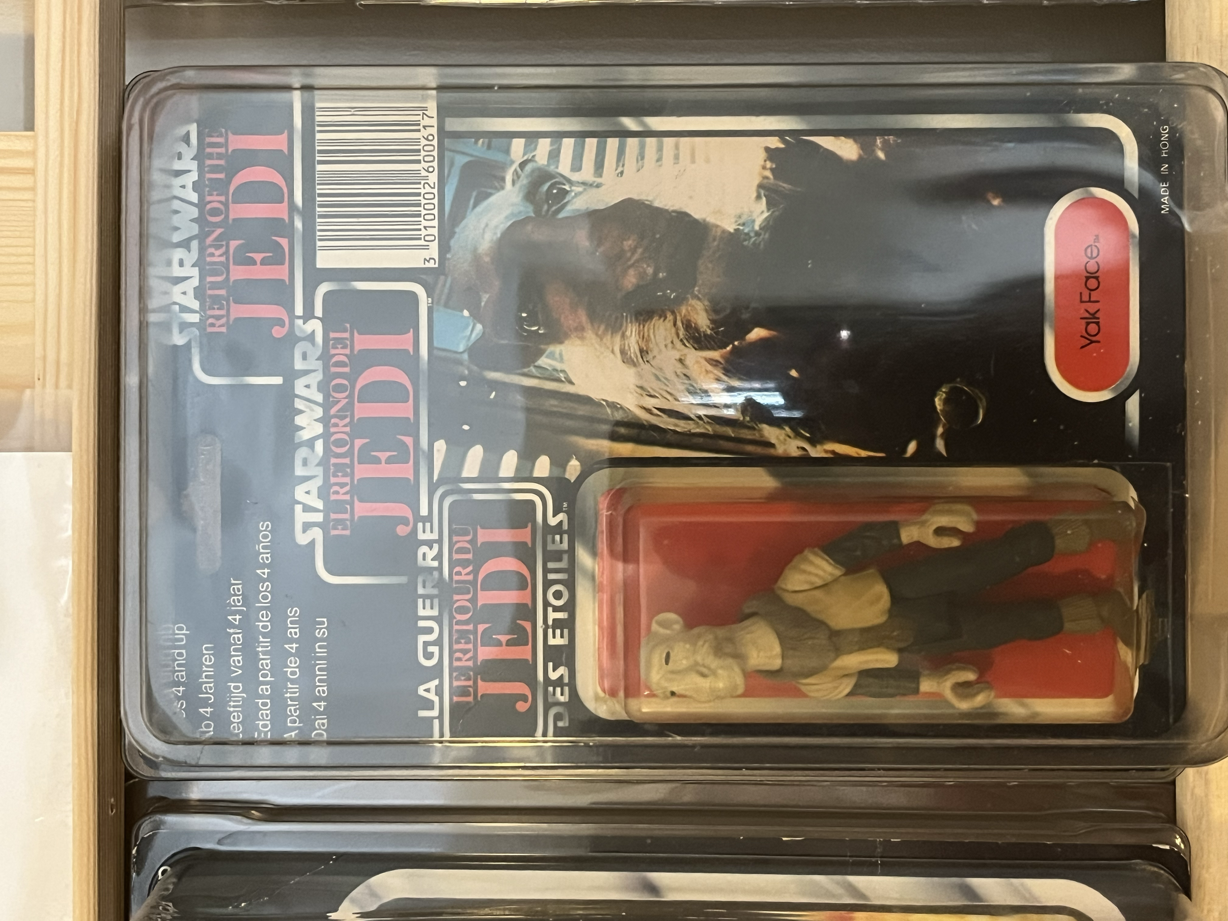A plastic toy figure of a dog inside a sealed plastic container with a paper insert that has text and an image of a dog on it.
