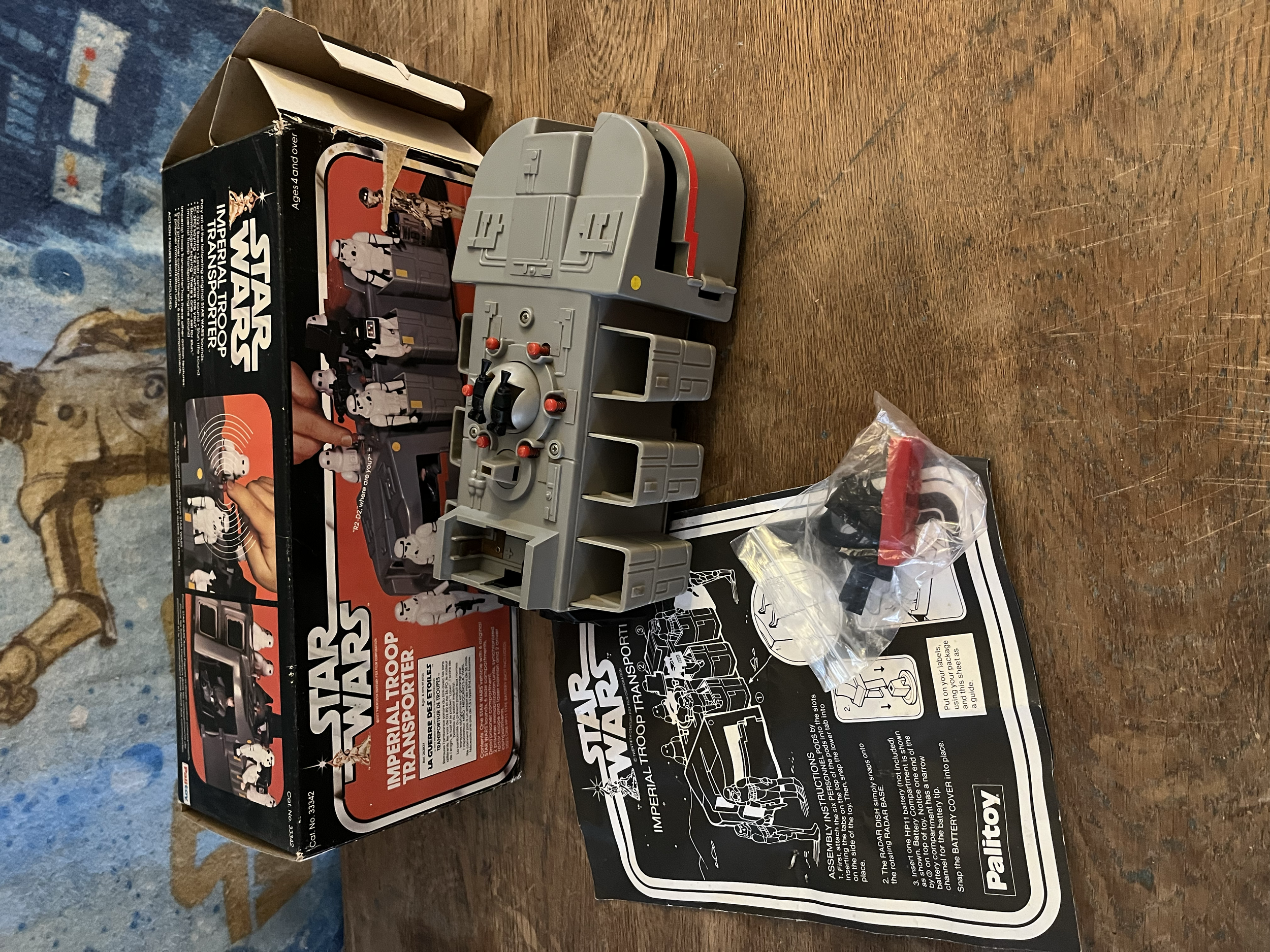 Star Wars Imperial Transforma Trooper toy packaging with the toy partially removed, lying on a wooden surface.