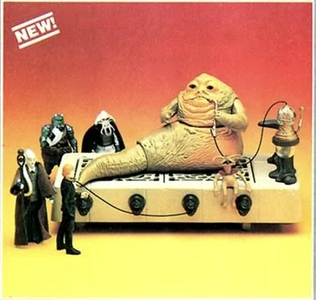 Toy figures of characters from Star Wars, including Jabba the Hutt, standing on a platform with a red background.