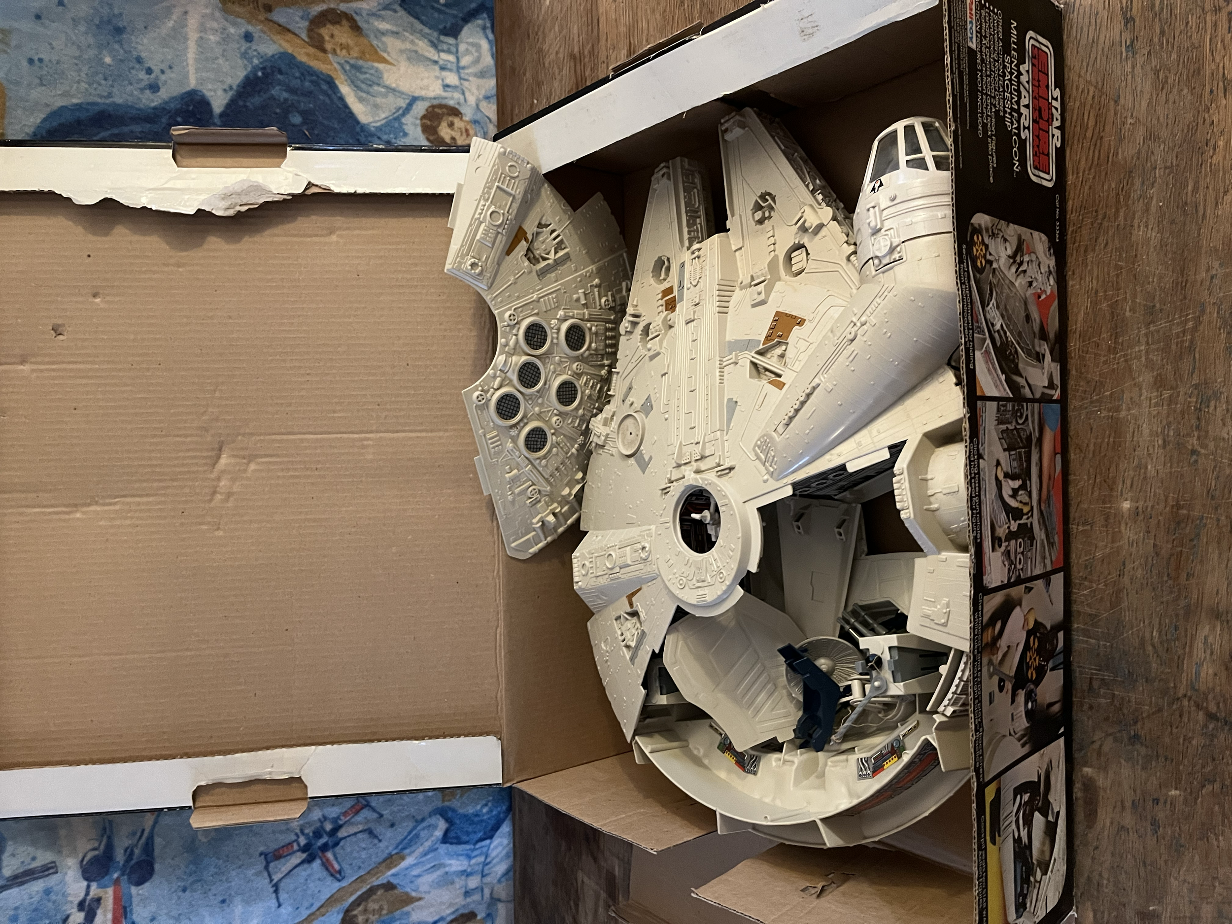 A model starship from the Star Wars universe, specifically a Millennium Falcon, assembled from plastic parts and placed on top of its original box.