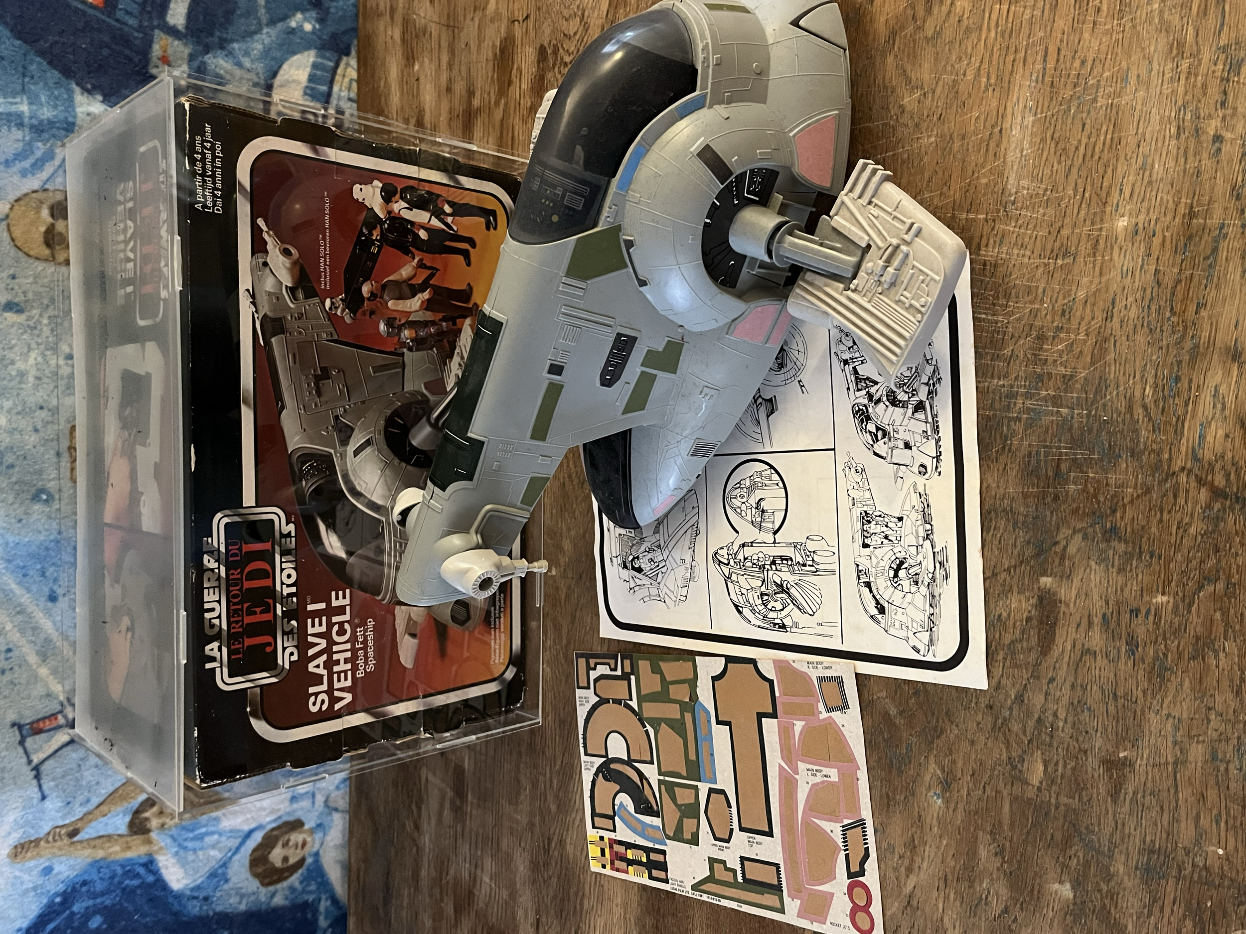 A model spaceship toy next to instruction sheet and a colorful map on a wooden table.