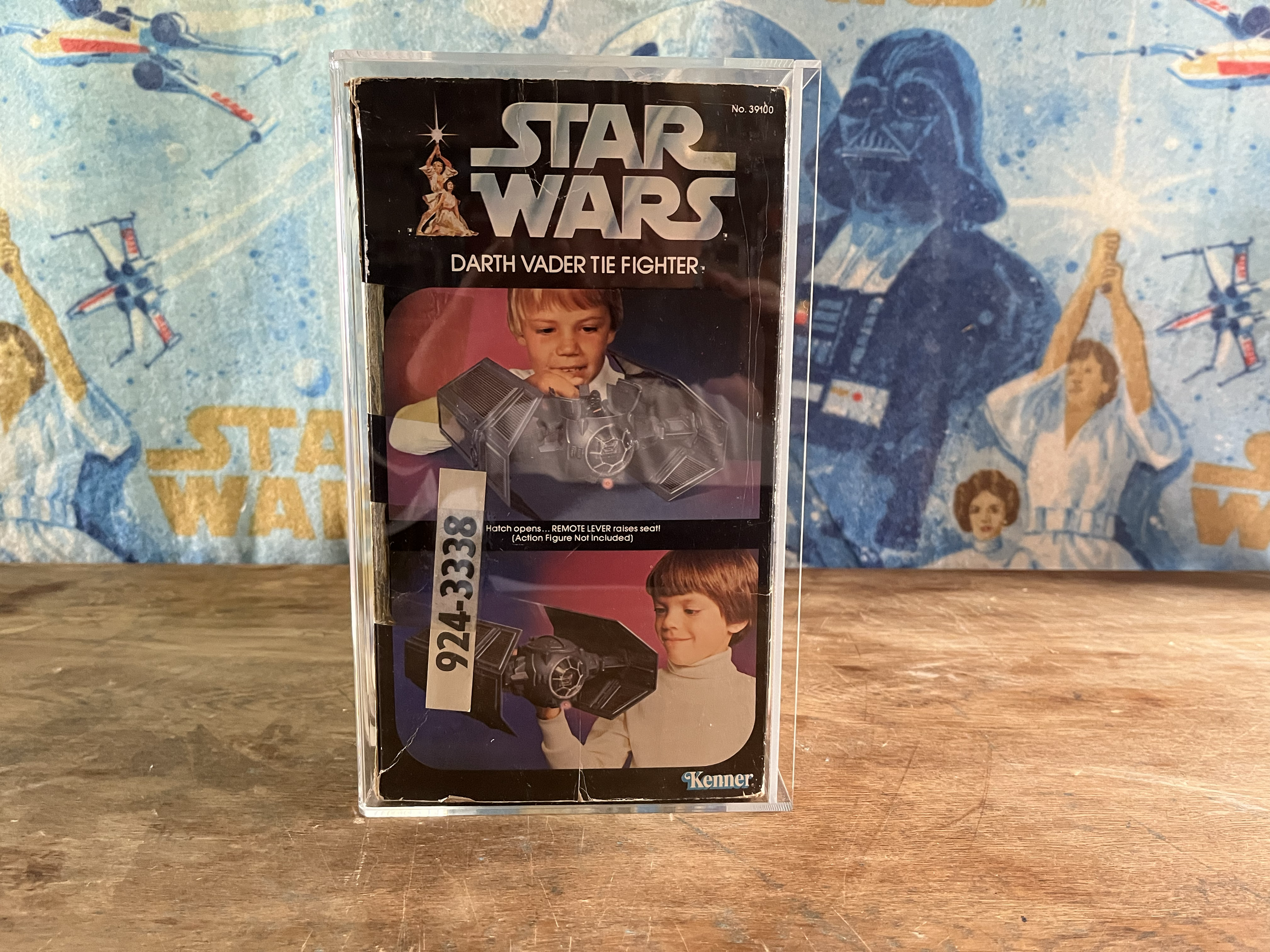 Star Wars vintage toy packaging featuring Darth Vader tie fighter with a photo of a boy playing with the toy and a background with Star Wars characters and spacecraft.
