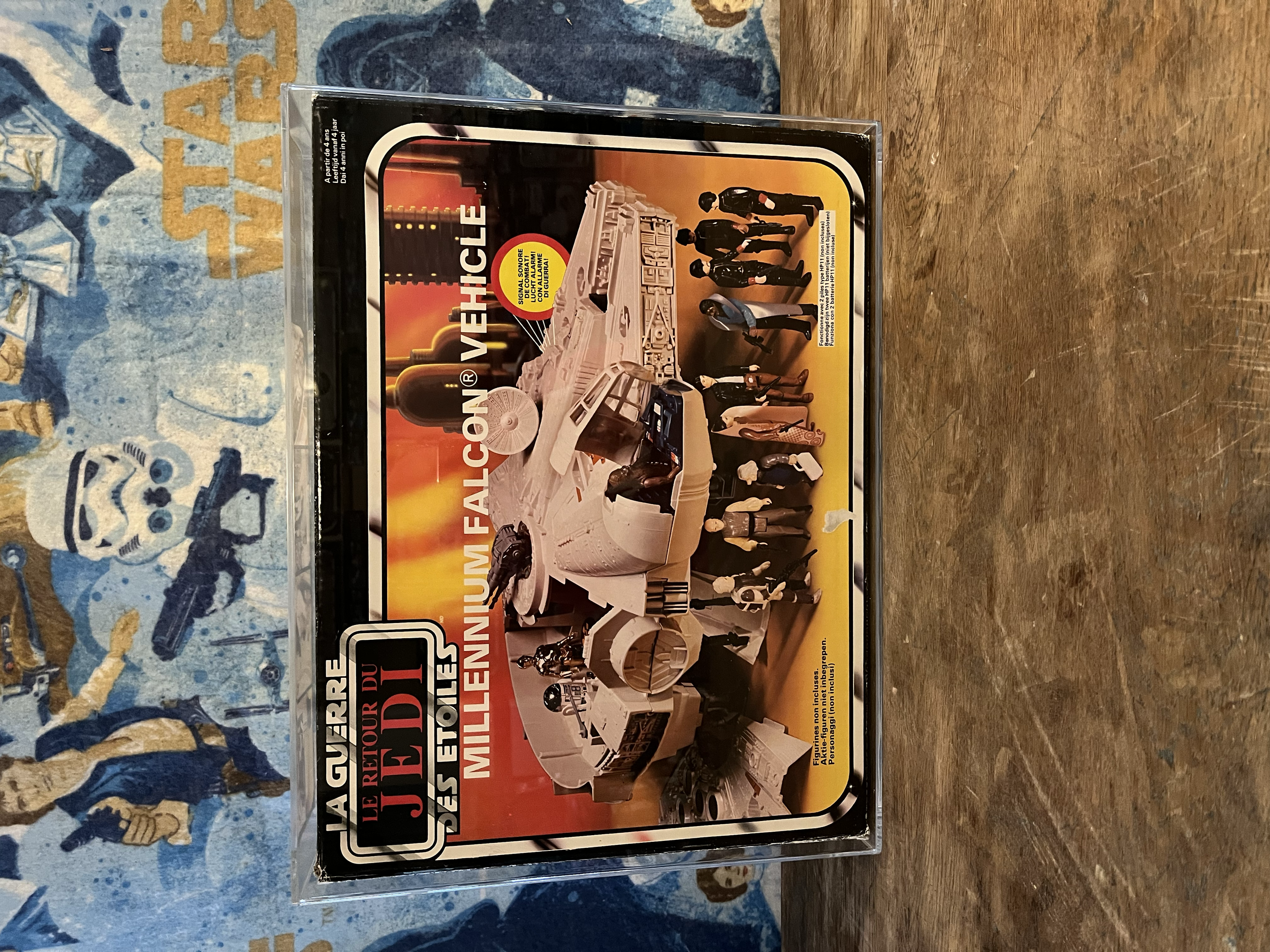 A vintage white toy helicopter with several small action figures around it, displayed on a rectangular box with a yellow background and black, red, and white text.