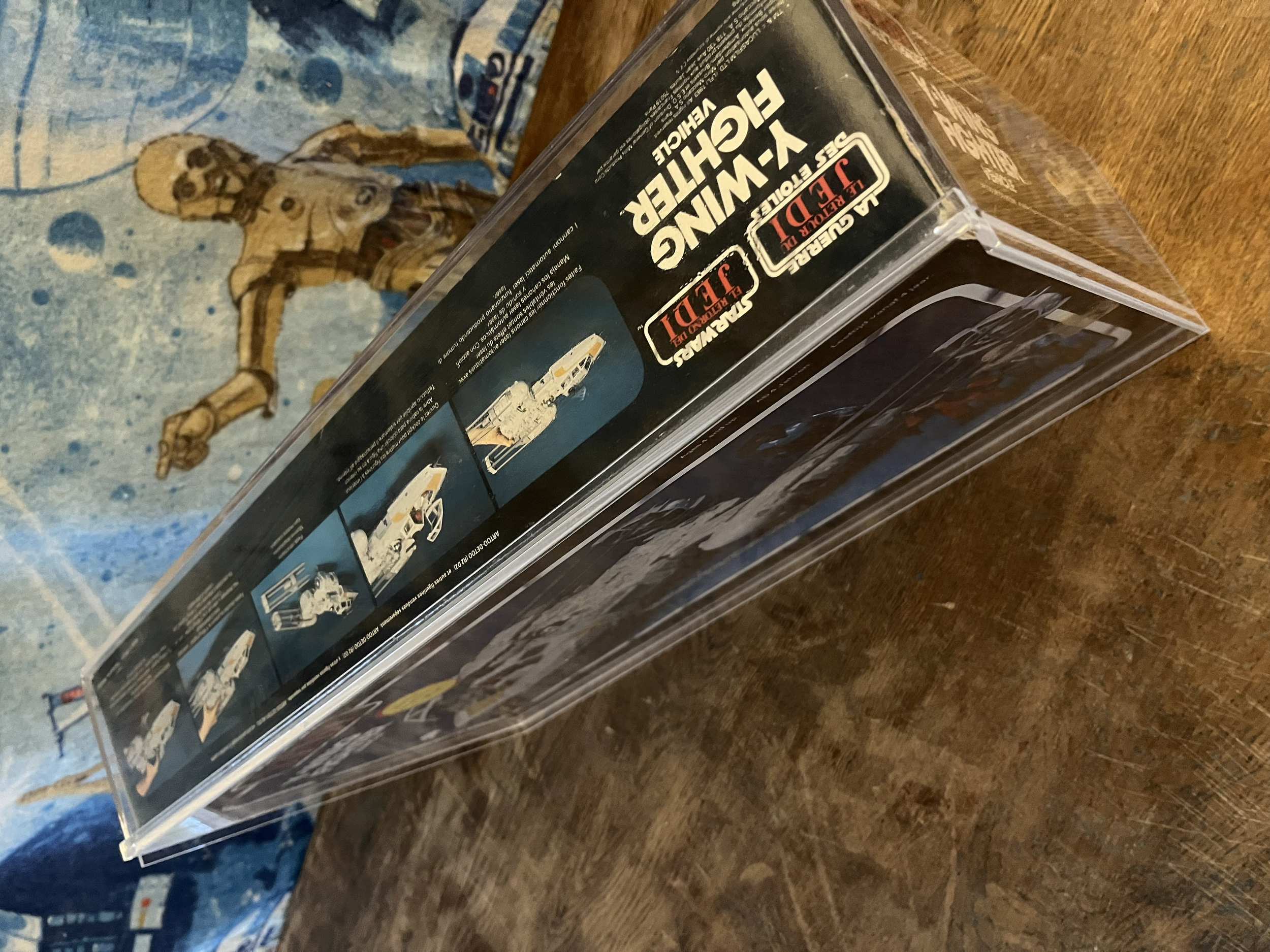 Box of model kits labeled 'Star Wars Y-Wing Fighter Vehicle' placed on a wooden surface. Part of the packaging is visible displaying illustrations of the Y-Wing Fighter spacecraft.
