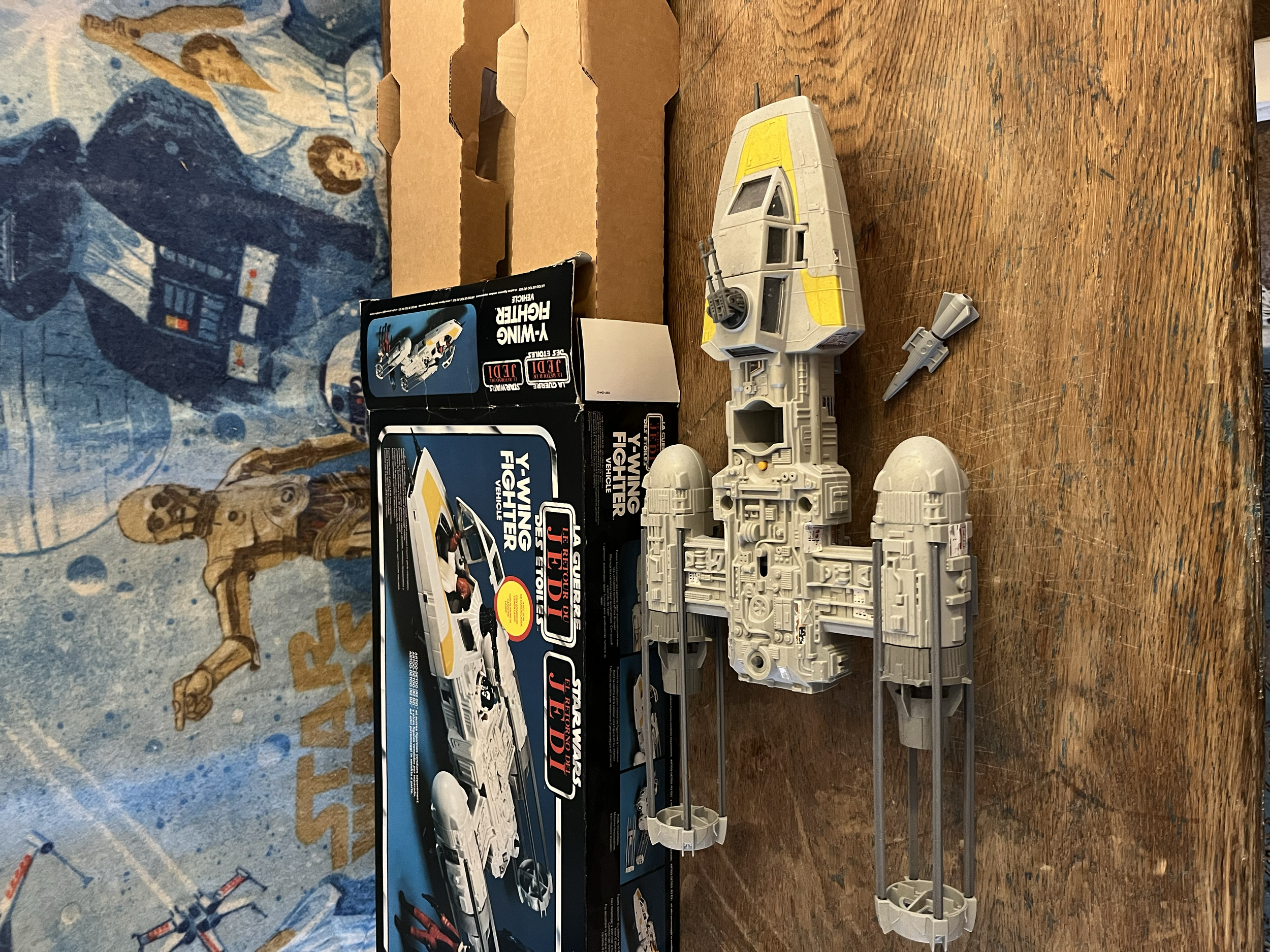 Star Wars Y-Wing Fighter model in assembly, with its box in the background, on a wooden table.