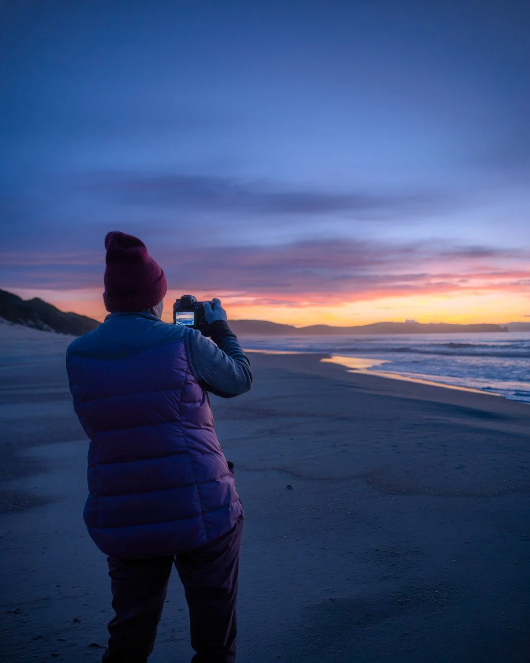 A photographer capturing sunrise on a beach at Bruny Island in Tasmania