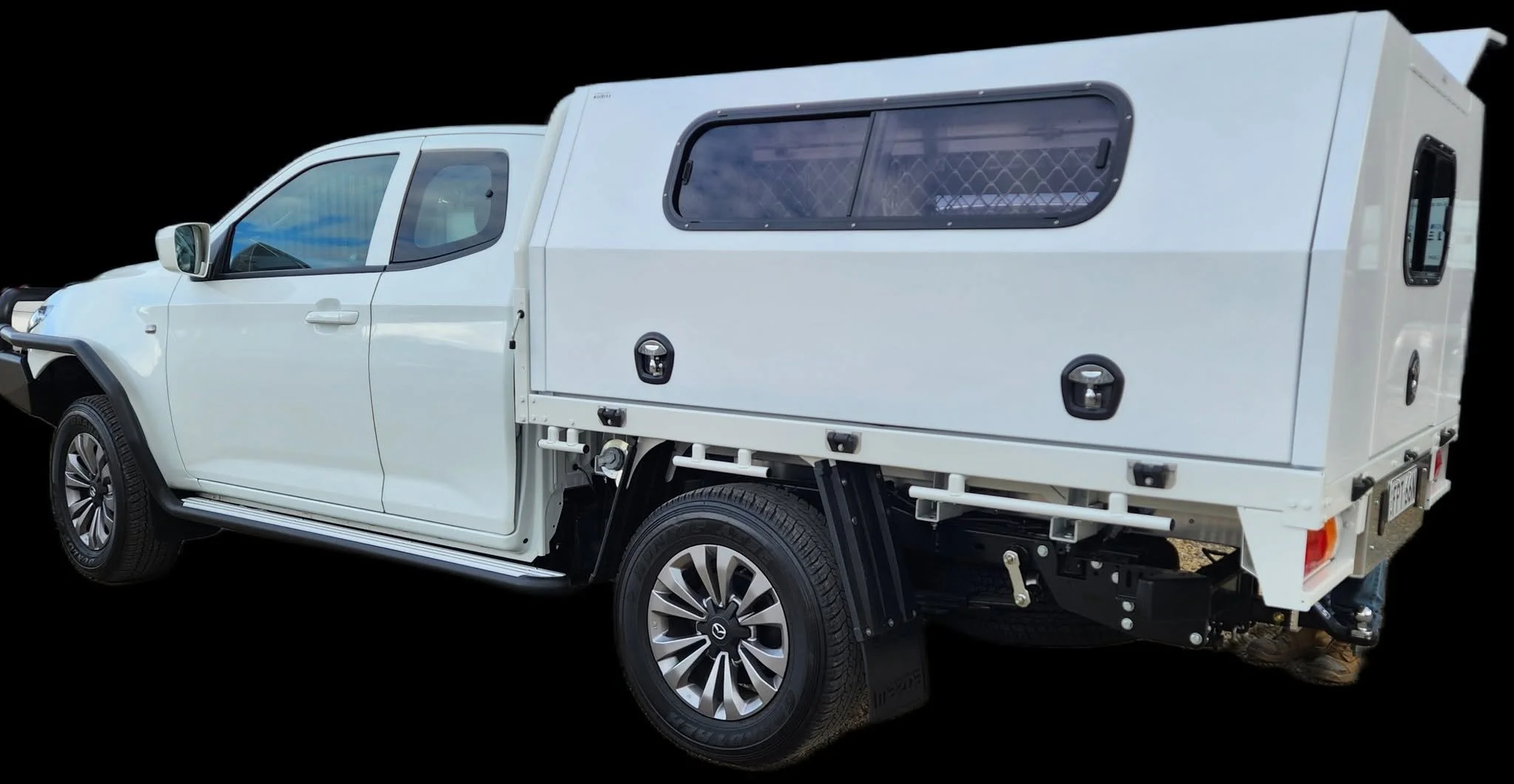 White pickup truck with a closed camper shell and equipment in the back