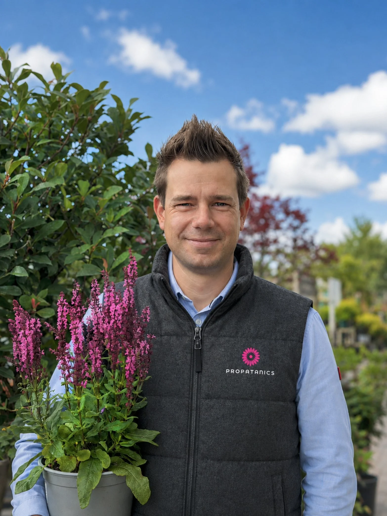 Steve Austin, founder of Propatanics, holding a flowering plant at a horticultural nursery.