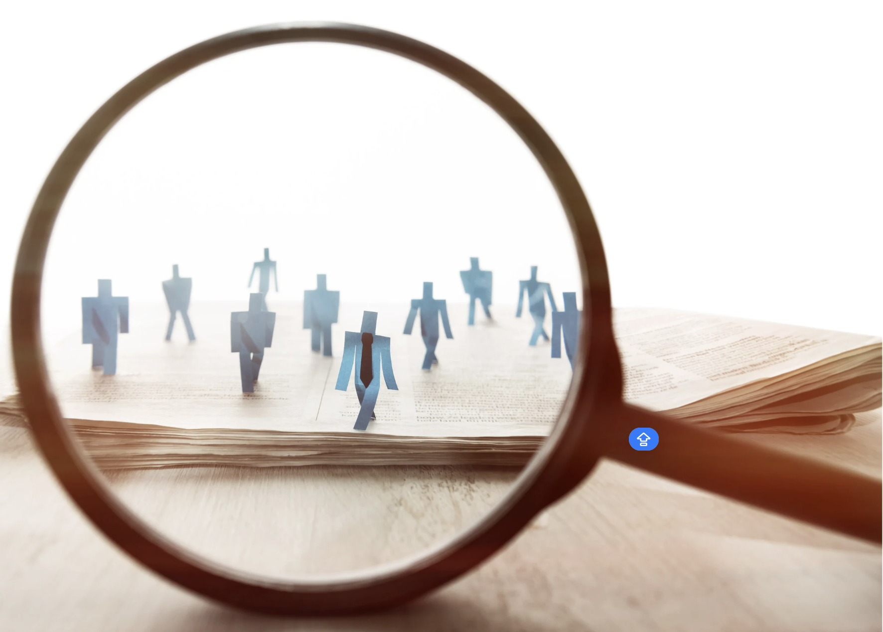 Paper figures in a book viewed through a magnifying glass.