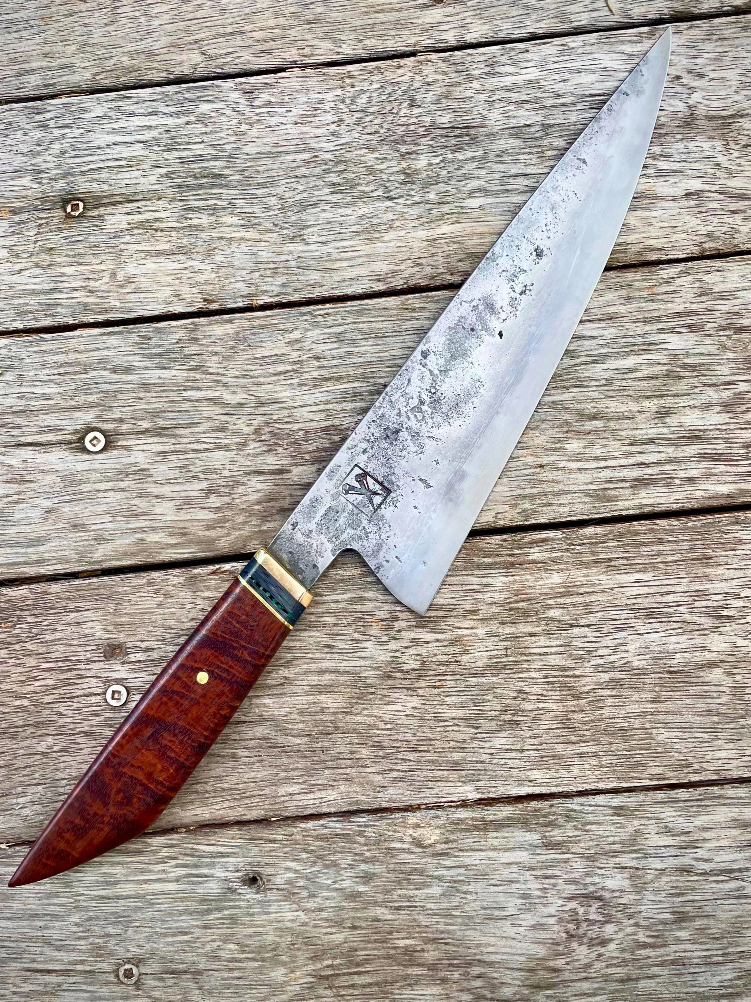 A kitchen knife with a wooden handle placed on a wooden surface.