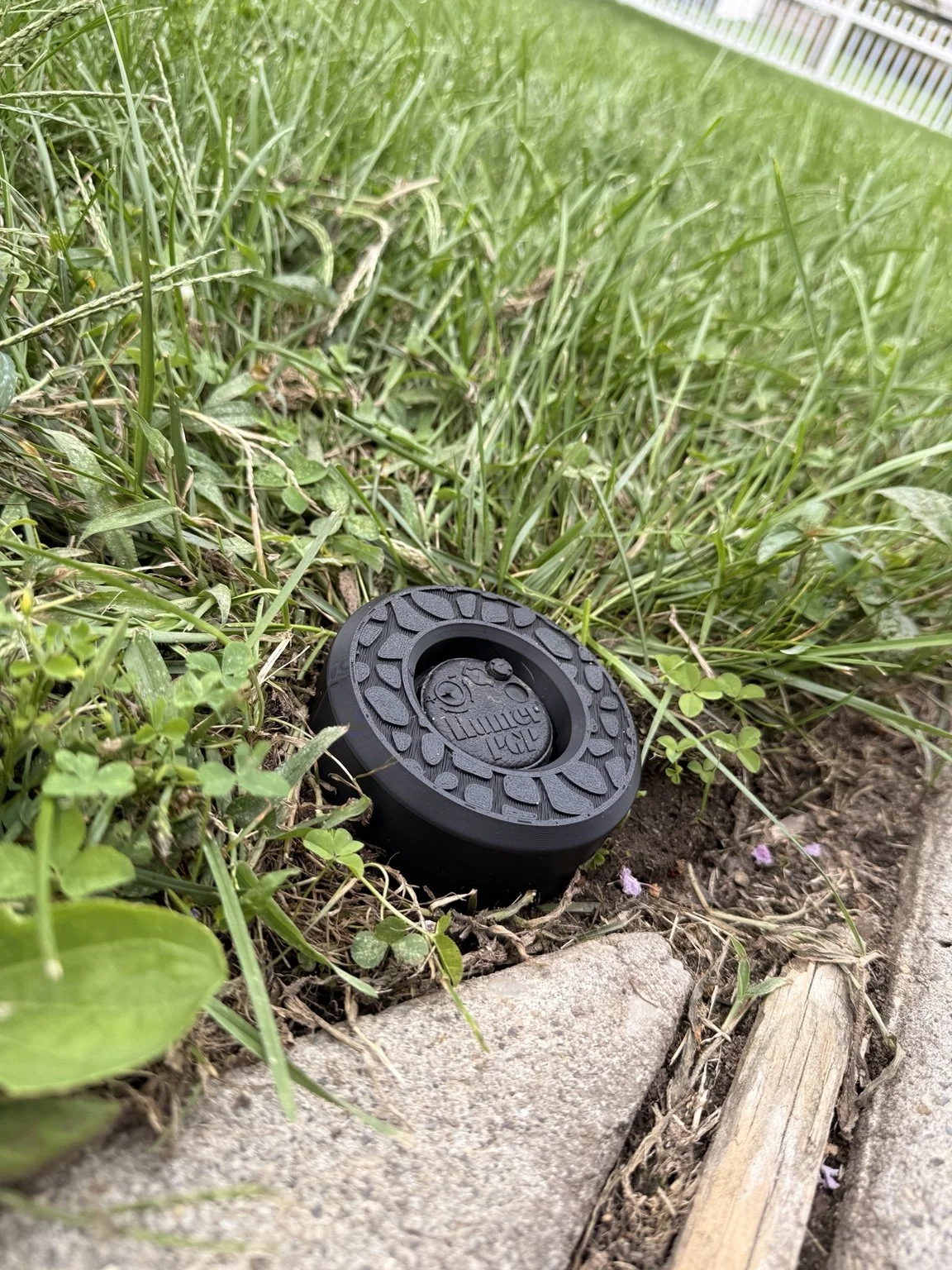 Black IngenioTech Labs sprinkler guard installed around a rotor head beside a lawn
