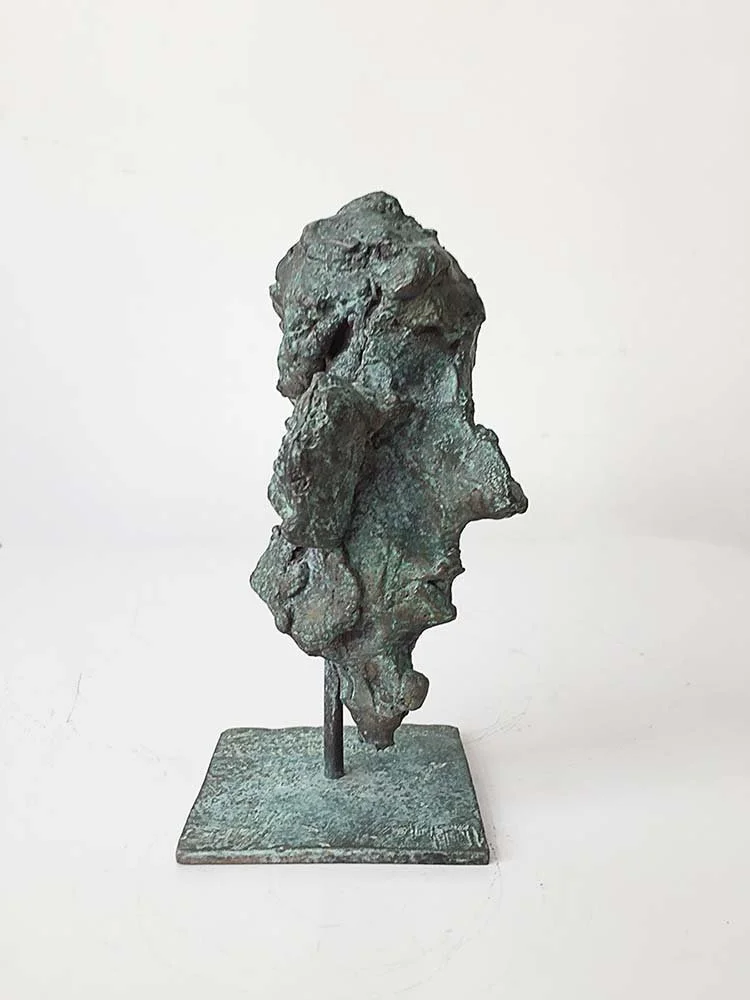 Bronze mask sculpture of a human face profile with a rough, abstract texture on a square base, 22 cm, 2015