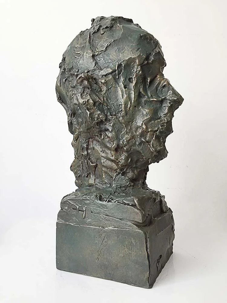 Bronze bust sculpture of a person's head and shoulders with rough texture on a rectangular base, 40 cm, 2015