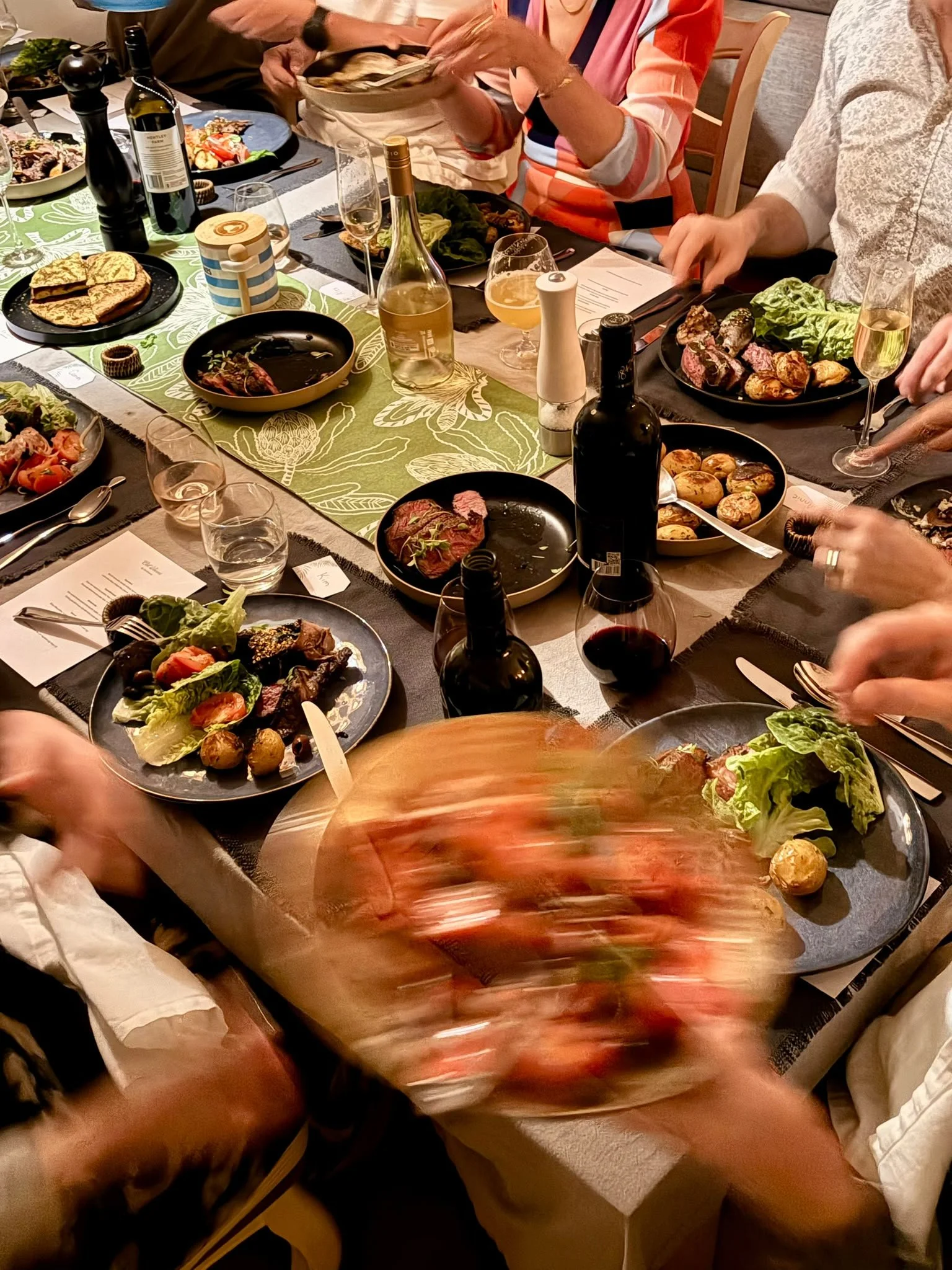 Family gathered around a dining table enjoying a meal with various dishes, drinks, and utensils.