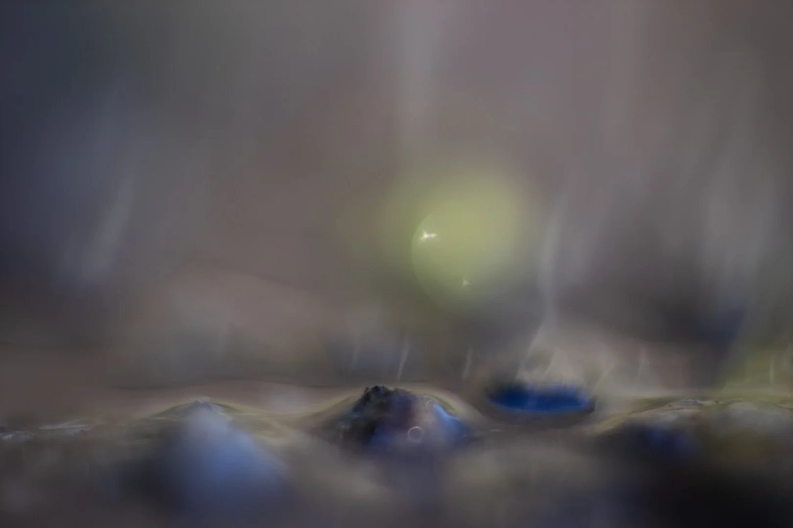 Image d'un paysage baigné d'une lumière surnaturelle en macrophotographie. Reflets dus aux aberrations optiques de l'objectif. 