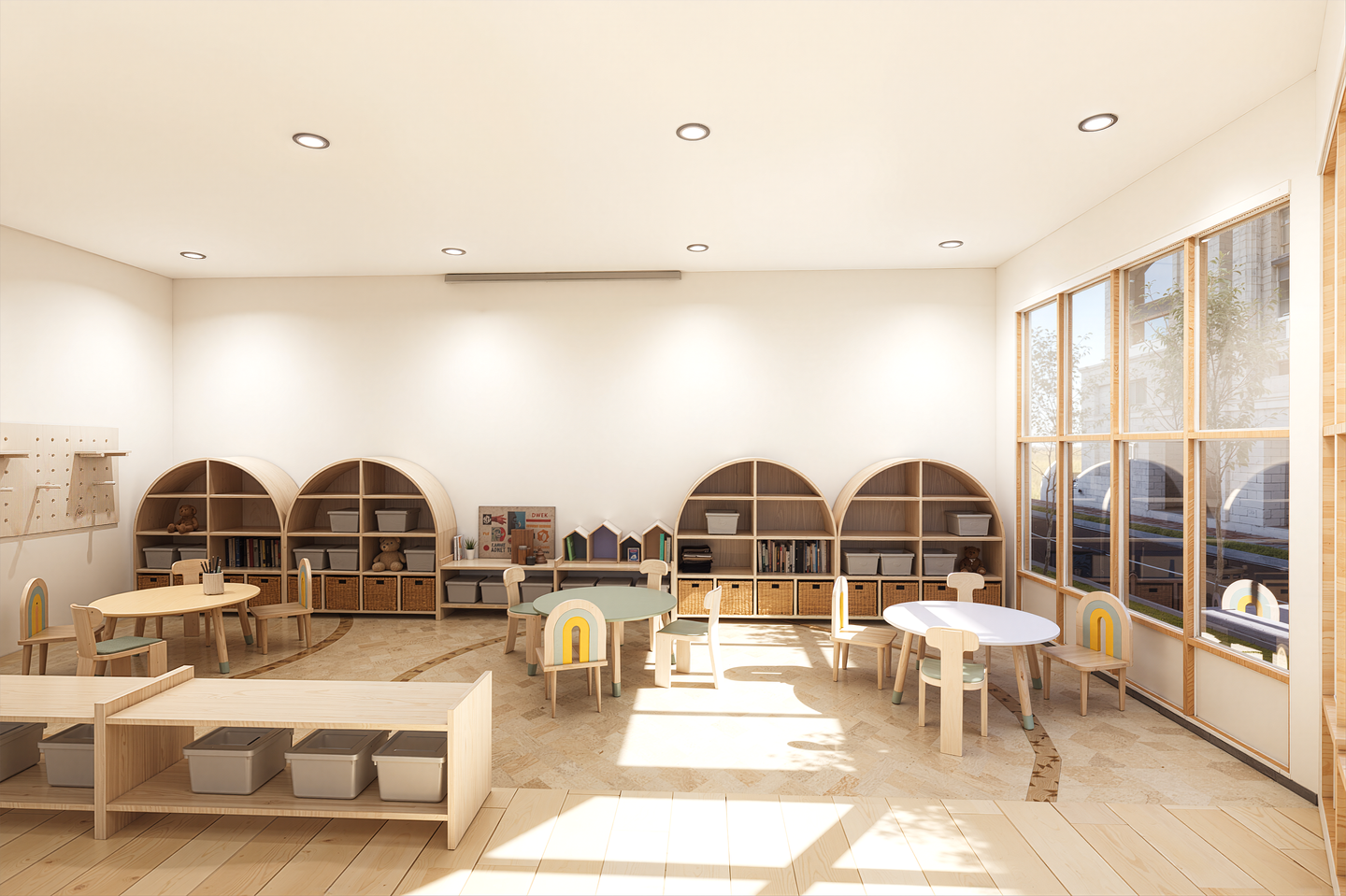 Bright and airy preschool classroom with light-colored wooden furniture, small round tables, chairs with rainbow and pastel accents, wall shelves with bins, and large windows letting in natural light.