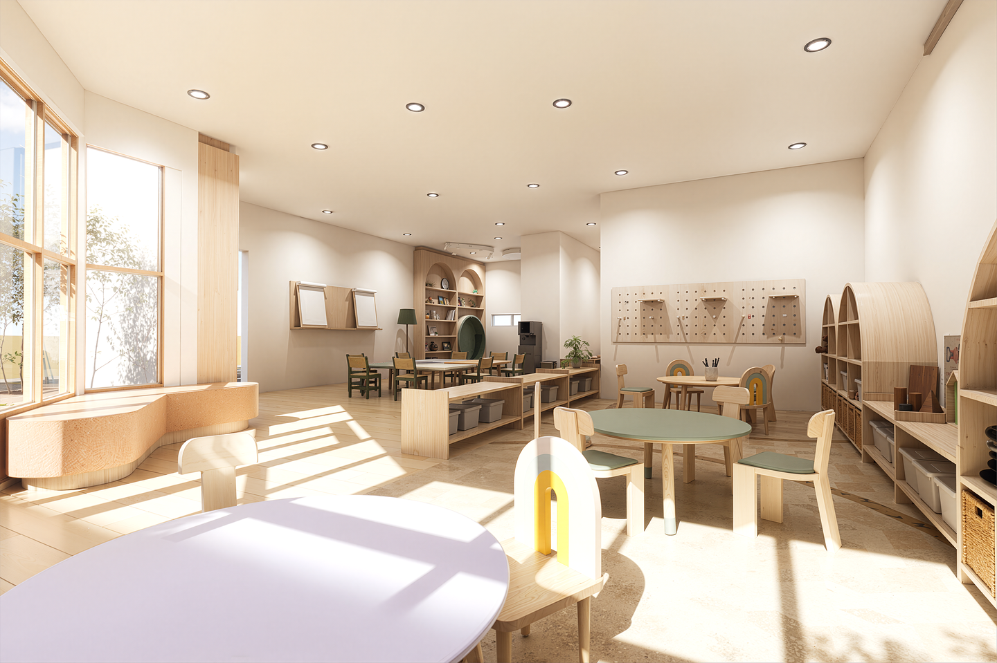 Bright, spacious classroom with wooden furniture, circular tables, shelves, and educational materials, natural light from large windows.