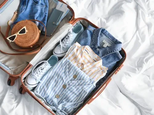 Open suitcase with clothes, shoes, and accessories packed for travel.