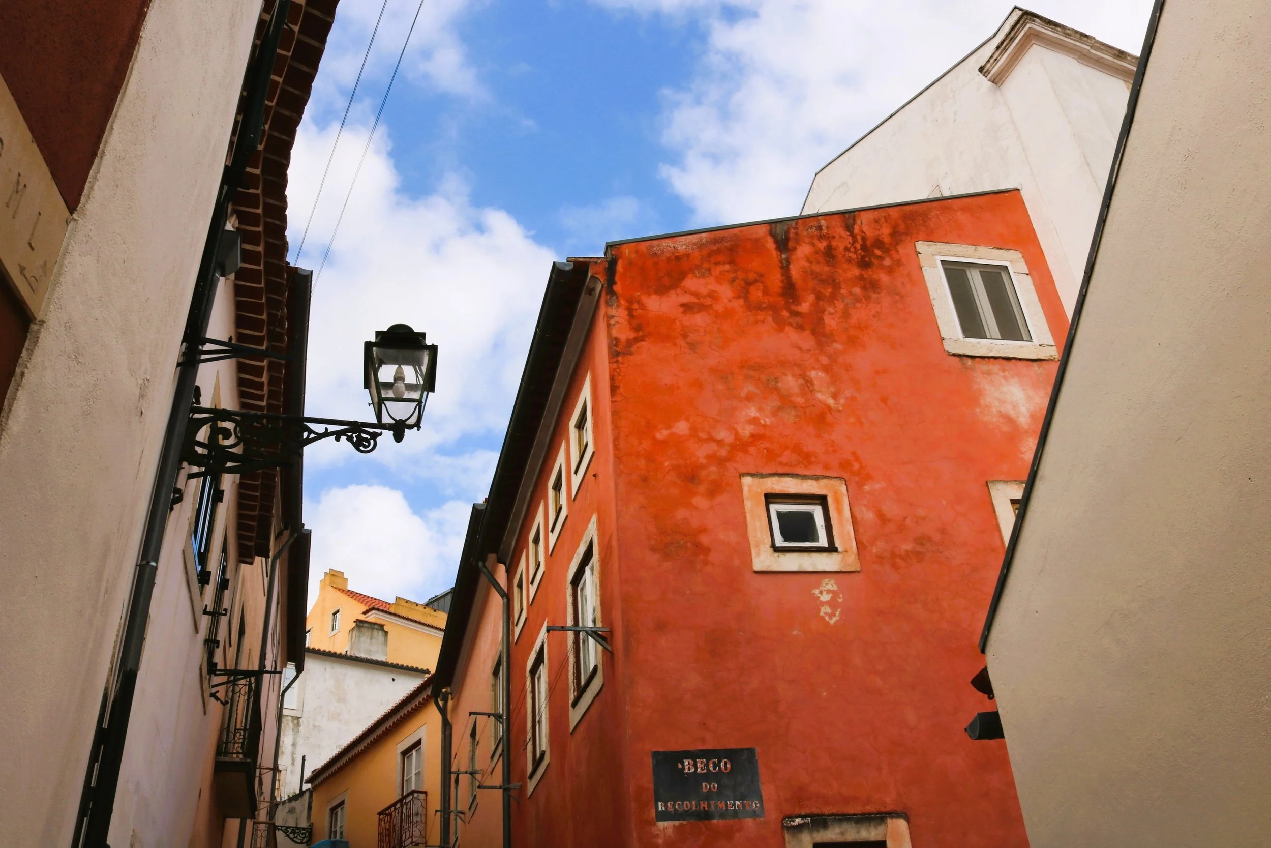 A downward perspective shot of colorful European-style buildings with a clear blue sky and scattered clouds above.