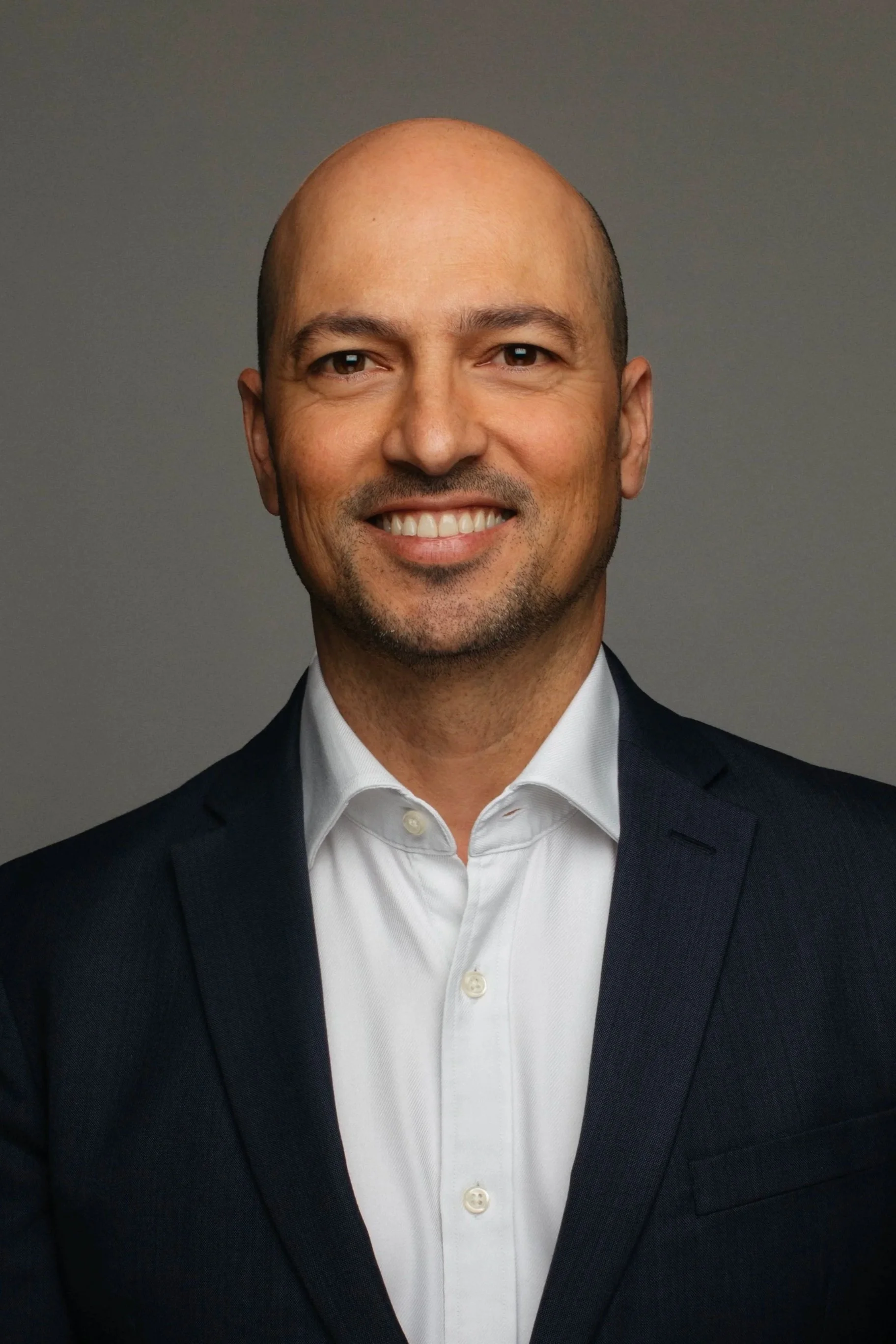 Headshot of Steve Muscat Azzopardi, co-founder of Career Circle Luxembourg, smiling at the camera in a dark suit and white dress shirt against a gray background.