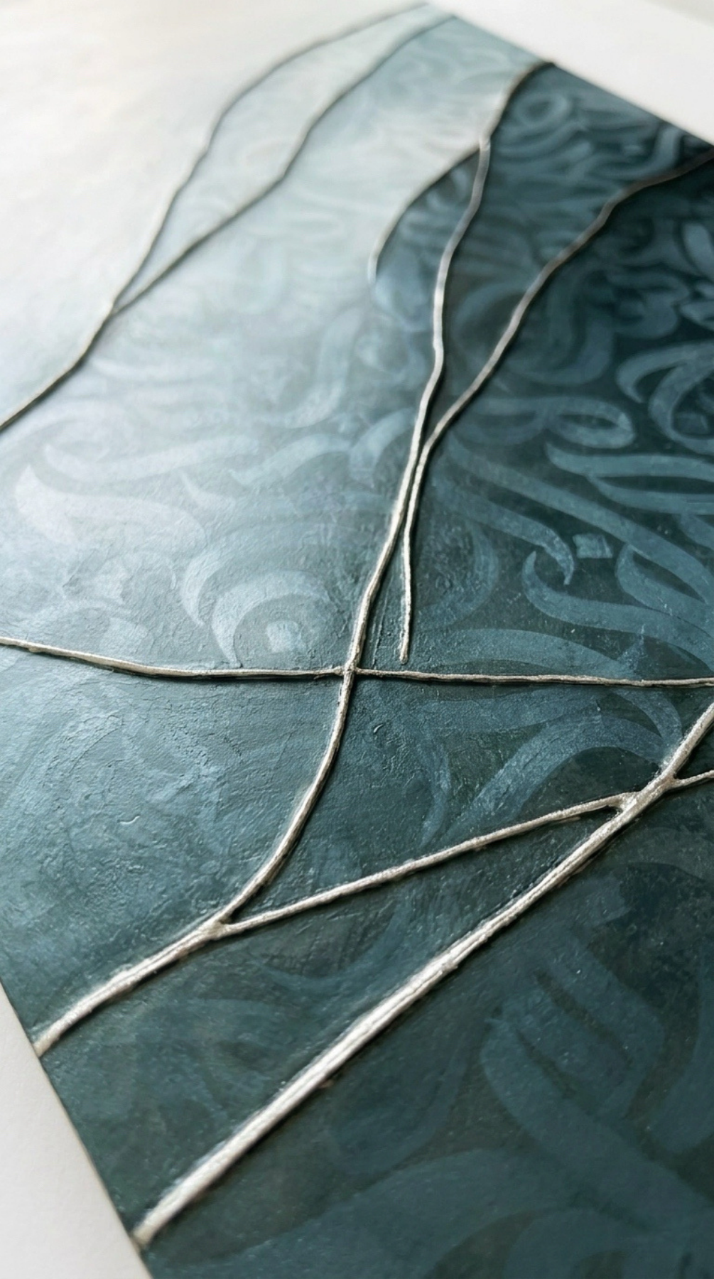 Close-up of an artwork, “Liminal Veil,” an original mixed-media artwork by Shirin Roshanaie, in shades of blue, green, white, and gold, featuring layered textures and Persian/ Arabic calligraphic forms and layered textures. . ShisArt Studio