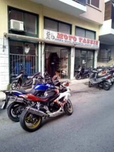 Motorcycles parked in front of a shop named "Moto Tassis".
