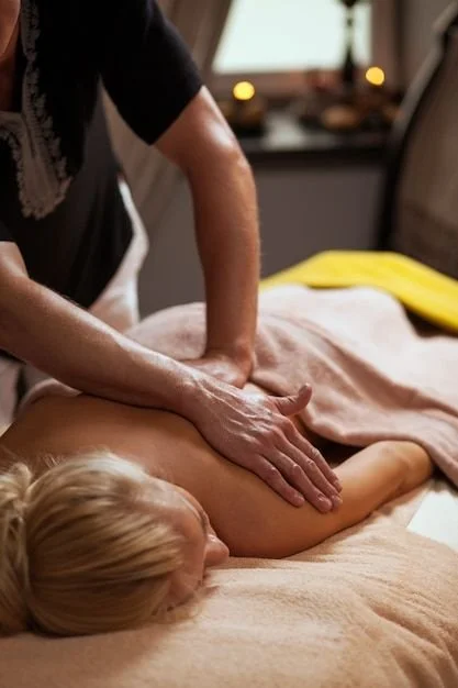 Persoon krijgt een rugmassage op een massagebank in een rustgevende kamer.