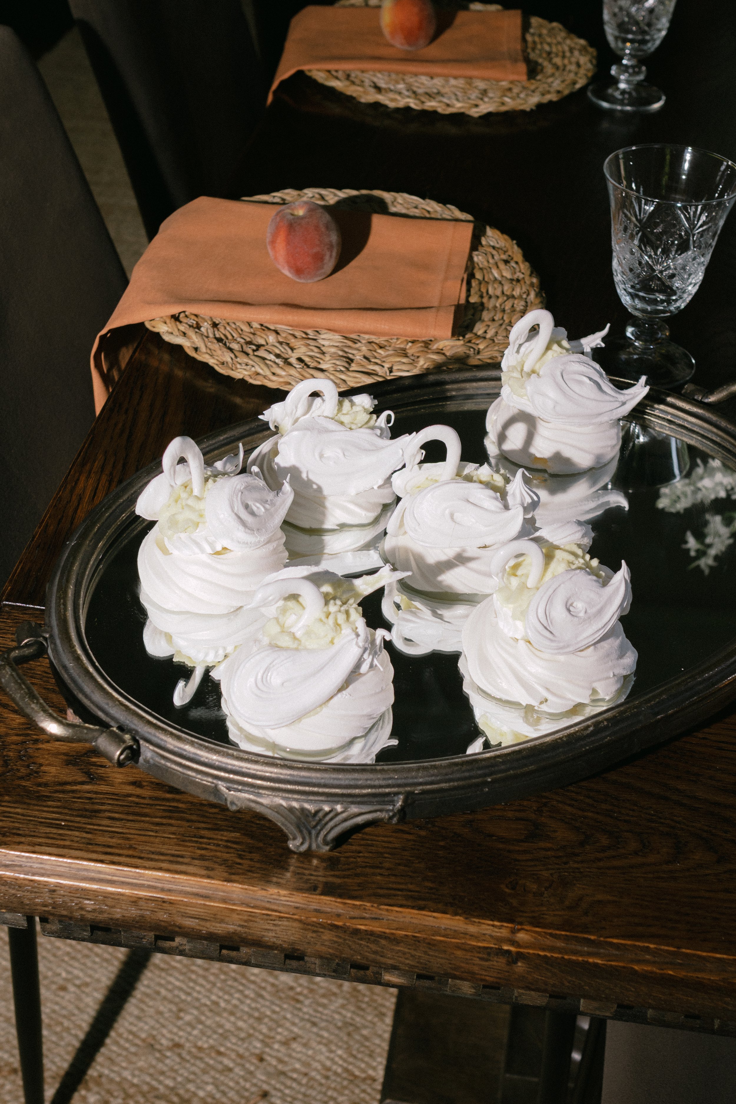 A silver serving tray filled with swan-shaped marshmallow desserts on a wooden table.