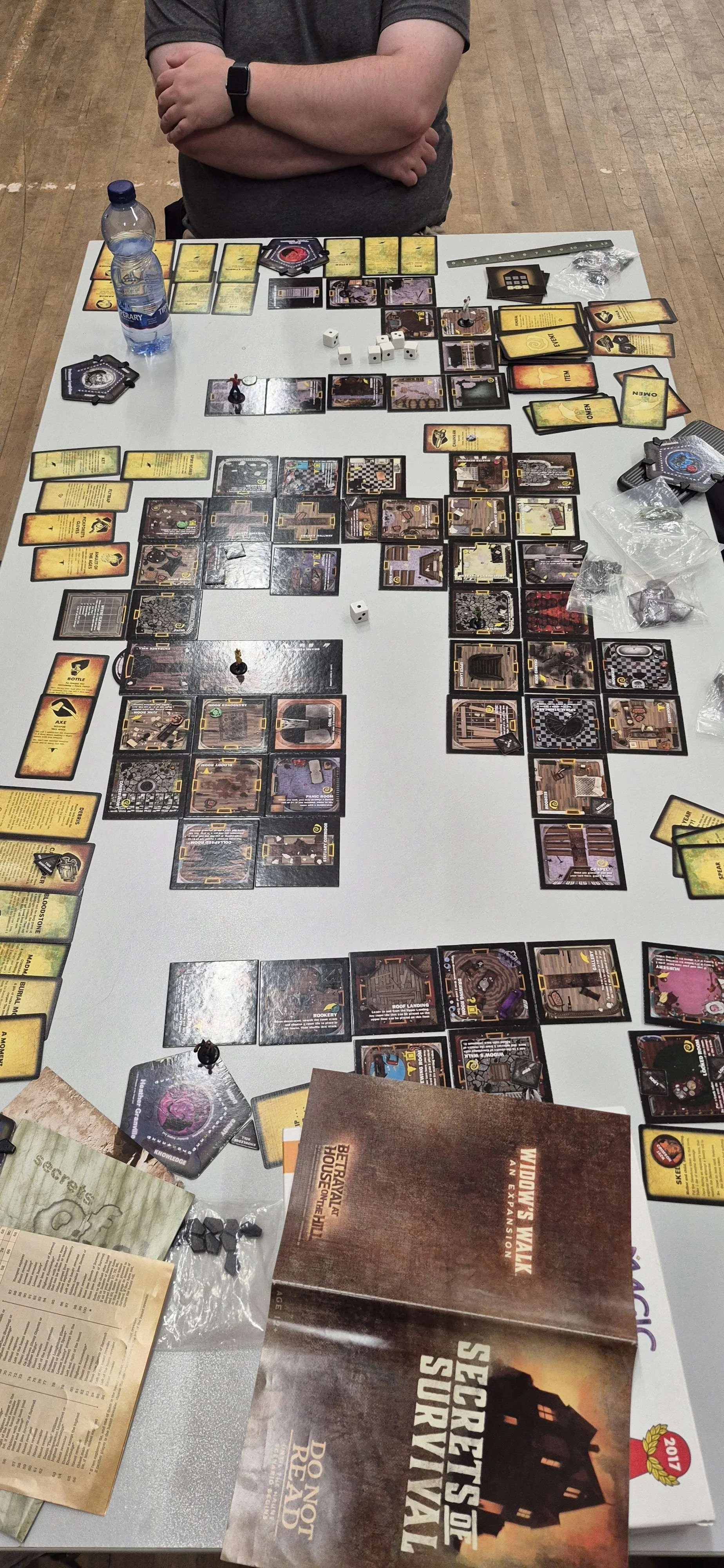 Tabletop game setup with various cards, tokens, dice, and rulebooks for 'Secrets of the House of the Dead: Do Not Go Gentle.'