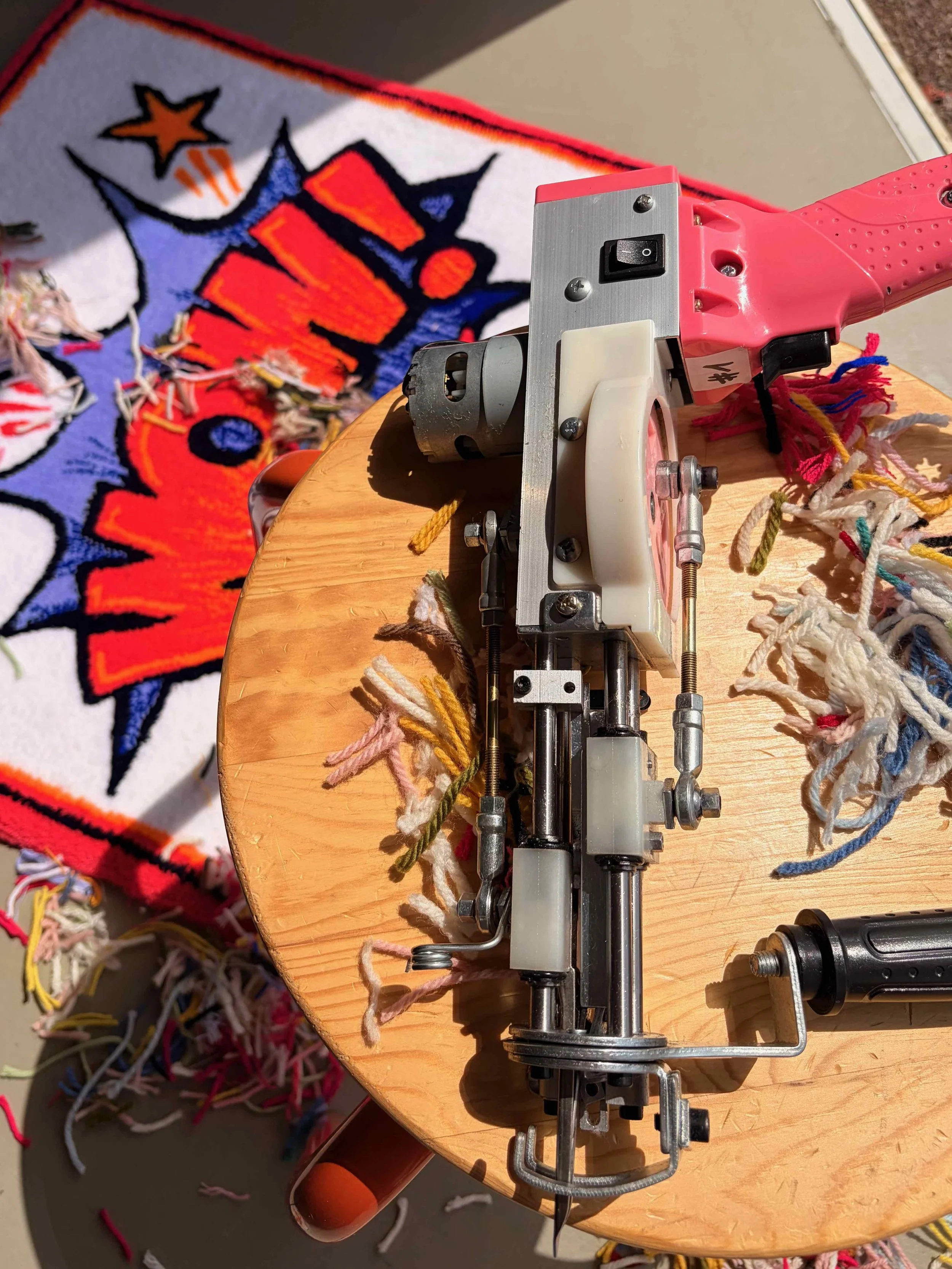 Close-up of an embroidery machine on a wooden table with colorful threads, and a partially finished embroidered design on fabric with a star and clock motif.