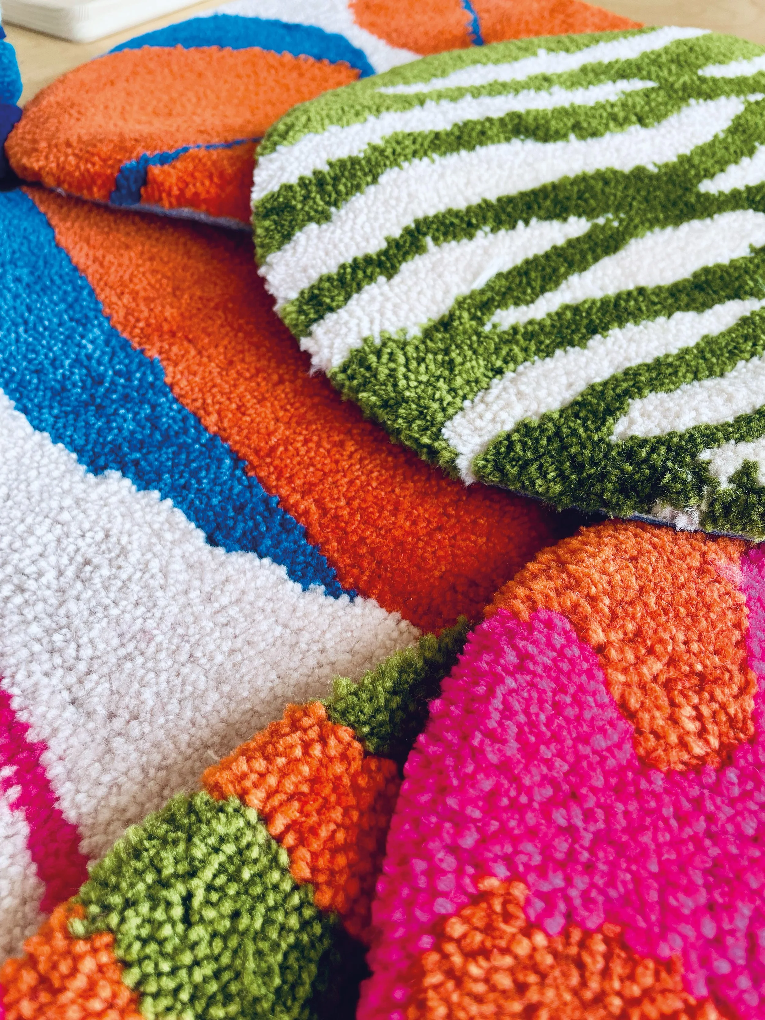 Close-up of colorful textured knitted or crocheted blankets with stripes of pink, orange, green, white, and blue.