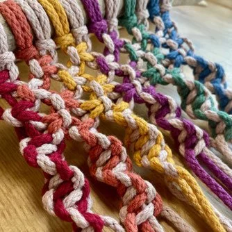 Colorful twisted yarn strands in red, pink, yellow, purple, blue, and teal, laid out on a wooden surface.
