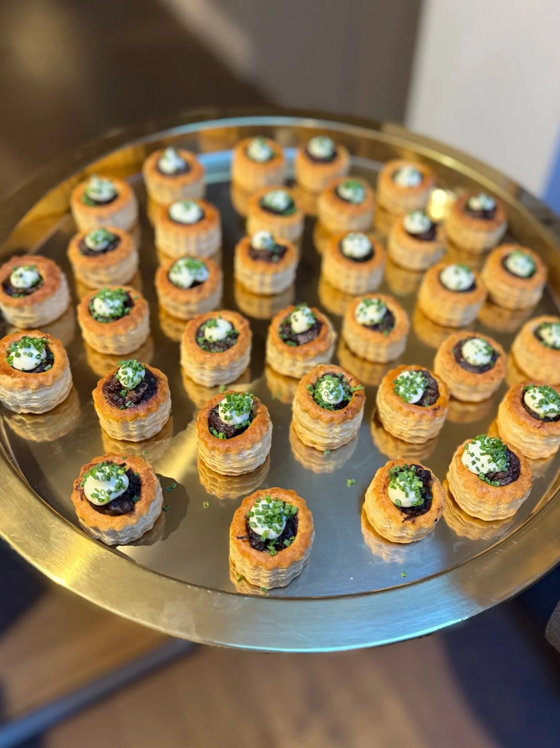 Assorted small appetizers arranged on a round silver tray.