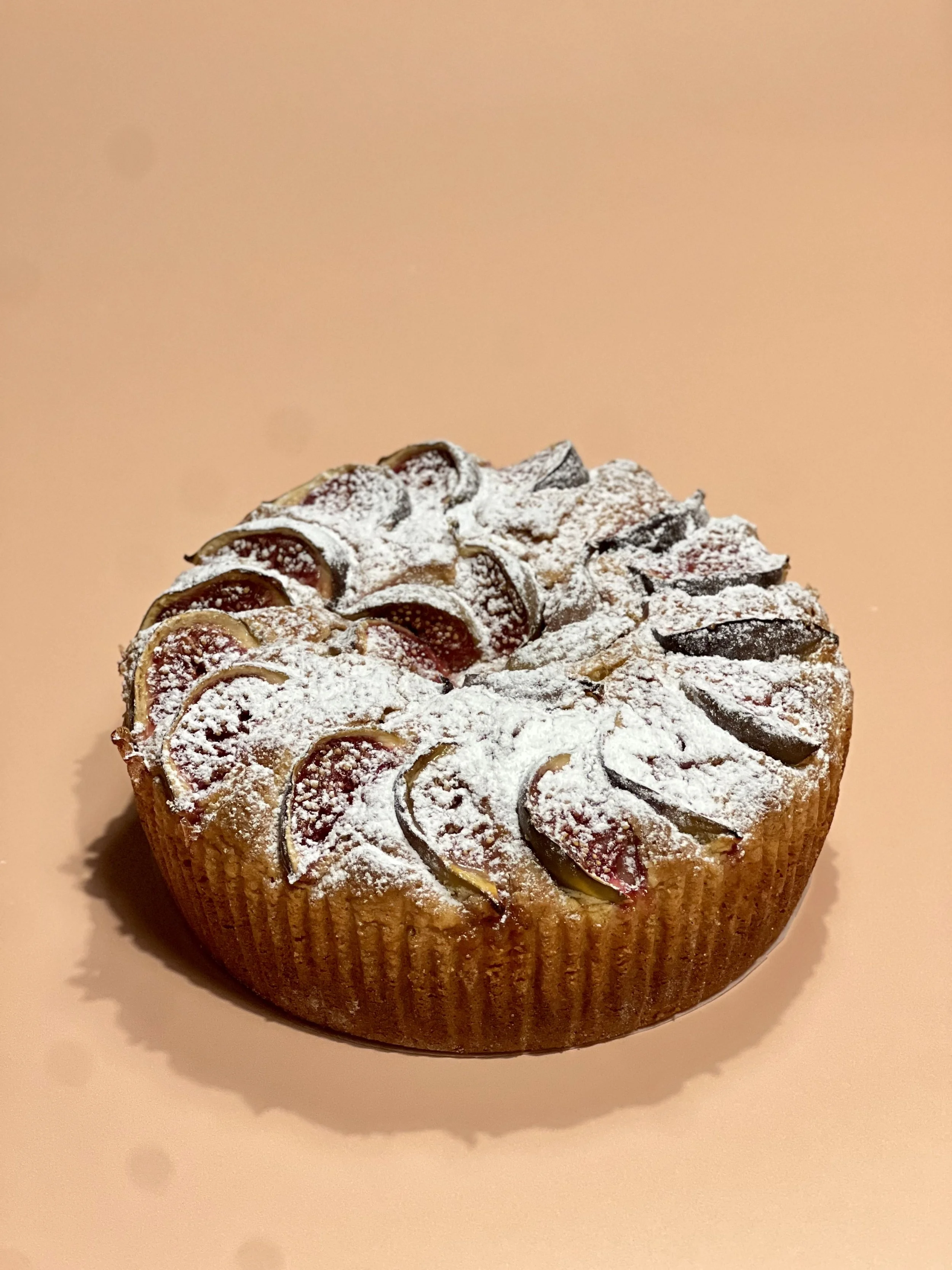 Close-up of a cupcake with frosting and fruit slices dusted with powdered sugar on top.