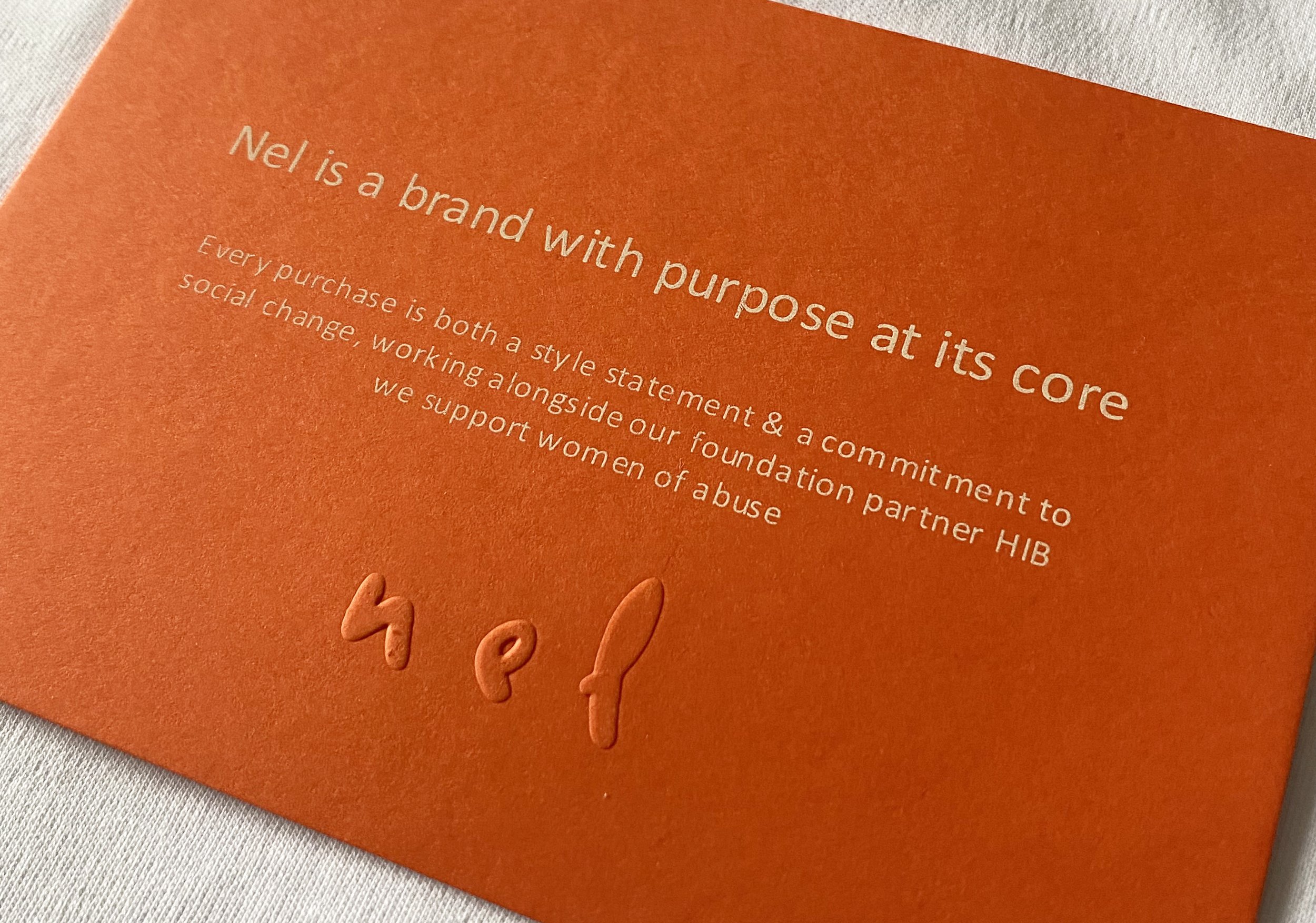 Close-up of an orange textured paper with white text saying 'Nel is a brand with purpose at its core'.