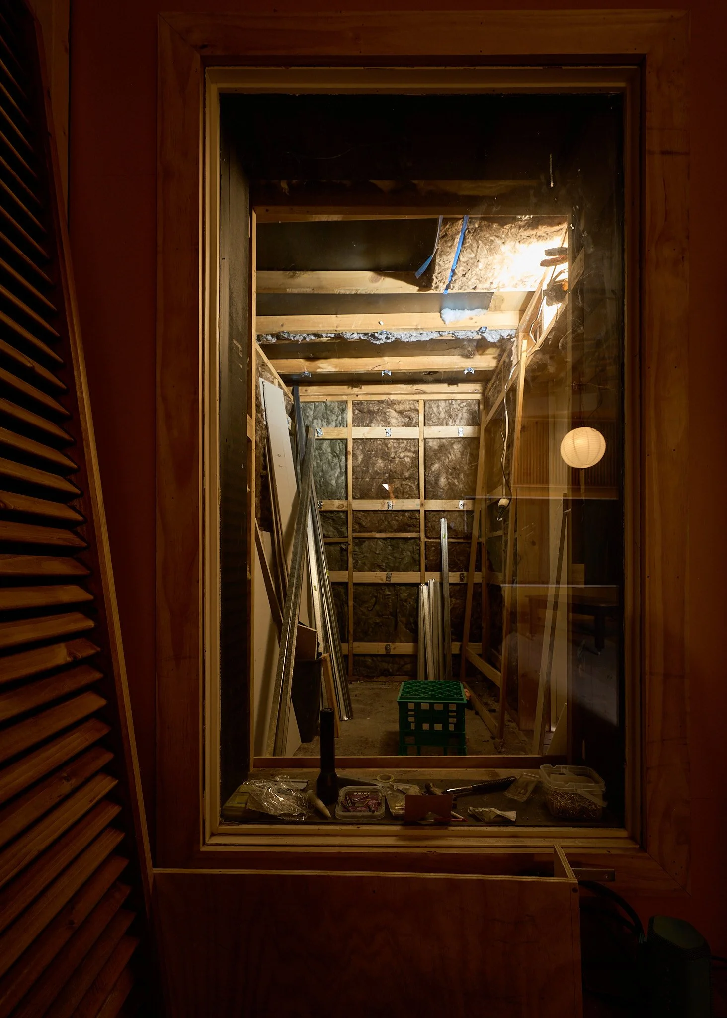 Interior of a room under construction with exposed wooden framing and tools on the floor.