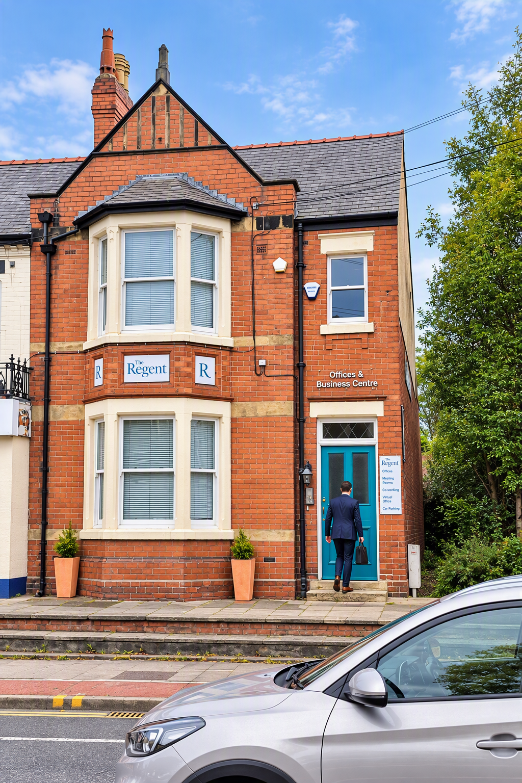 Brick building with a blue door, white window frames, and a sign reading 'Offices & Business Centre.' A man in a suit carries a briefcase, walking toward the door. There are potted plants on the sidewalk and a silver car partially visible in the foreground.