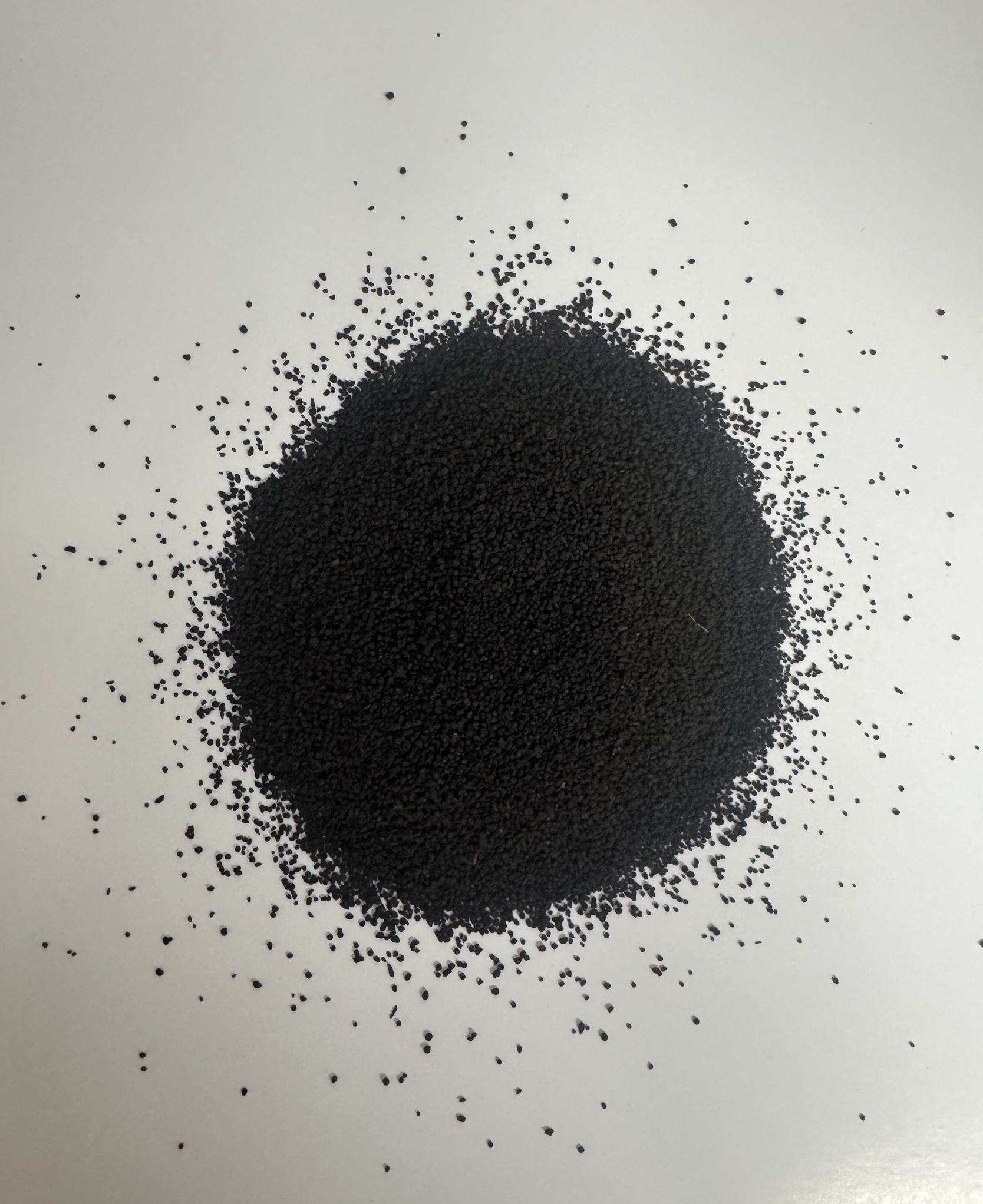Close-up of a pile of small black seeds with some scattered around on a plain white background.