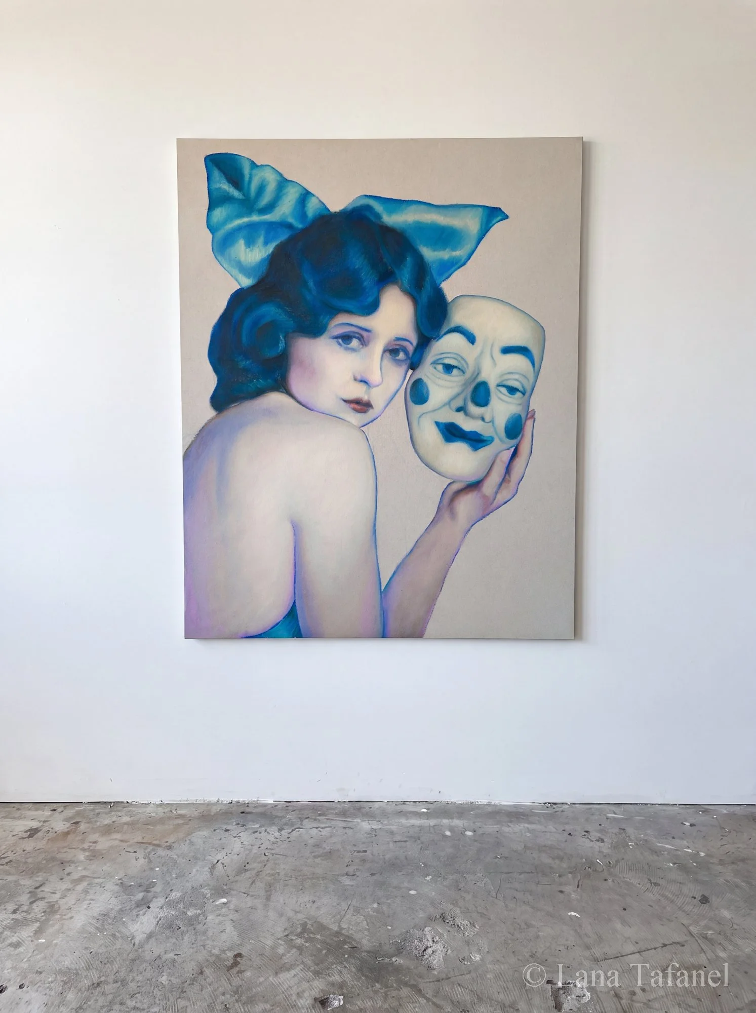 A painting of a woman with blue hair holding a clown face mask, displayed against a plain white wall in an art gallery.