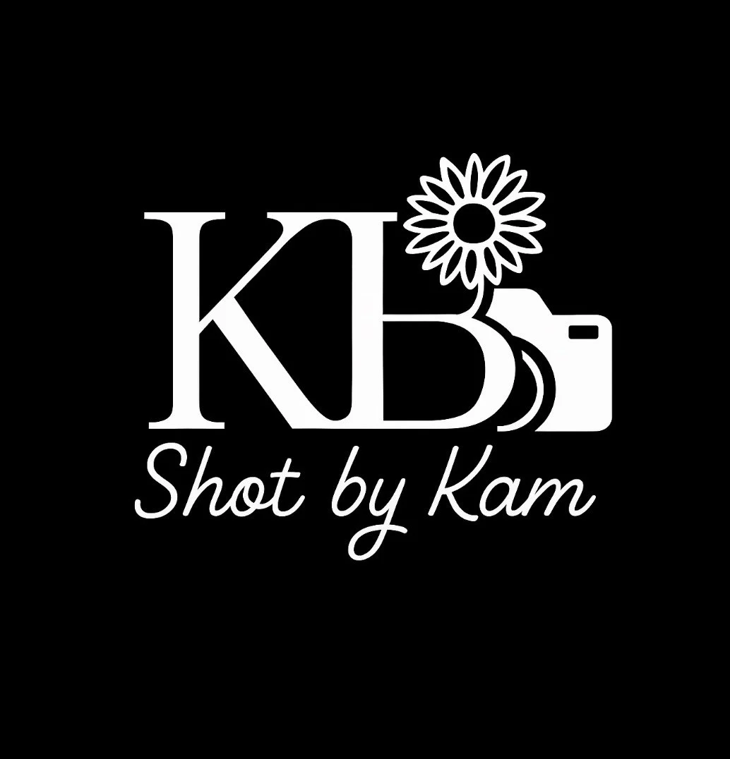 Black background with white logo featuring large initials 'K' and 'B', a sunflower, a camera icon, and the text 'Shot by Kam'.