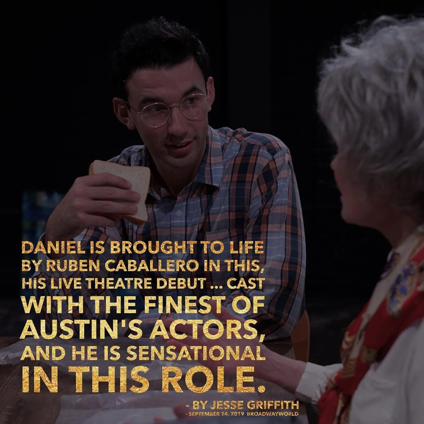 A young man in glasses and a plaid shirt sitting at a table, holding a sandwich, talking to an older woman with white hair and a patterned blouse, in a dimly lit setting.
